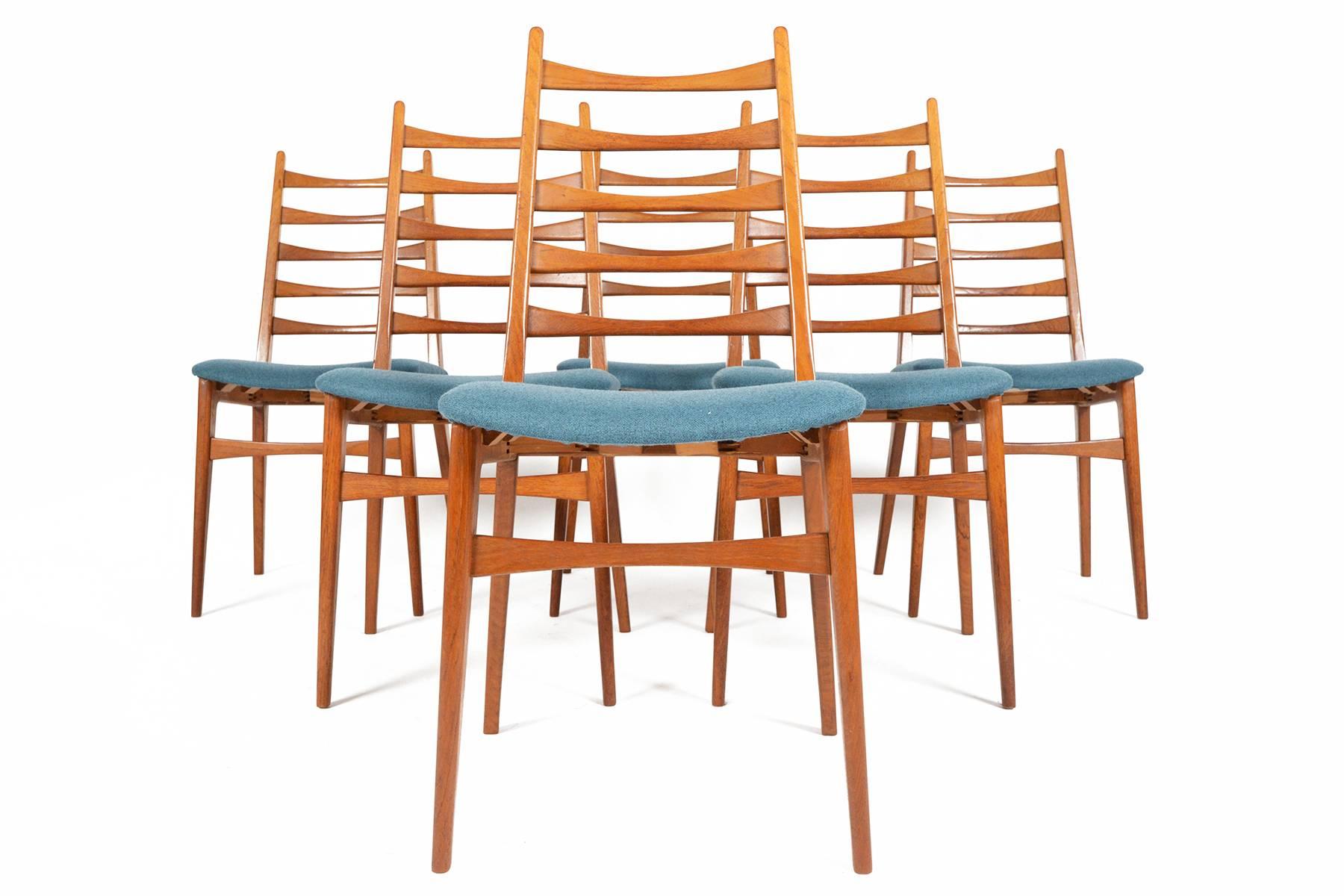 This set of six Danish modern ladder back dining chairs in teak evoke the elegant style of Niels Kofoed. Five atomic bowtie spokes offer support and structure to each frame. Seats have been recently upholstered in cerulean wool from the 
