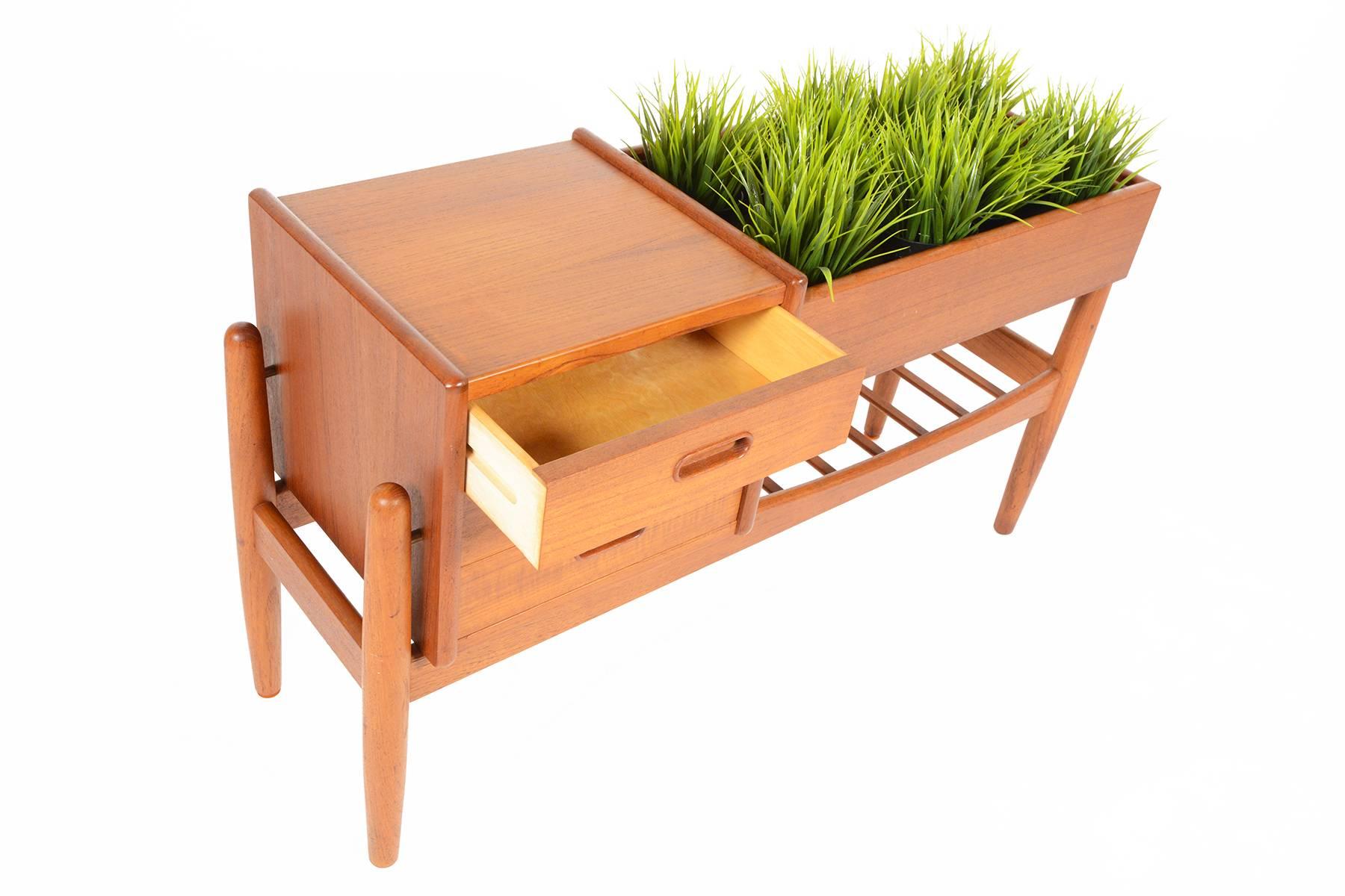 This Danish modern teak entry chest with planter No. 36 was designed by Arne Wahl Iversen for Vamo Møbelfabrik and is perfect for any modern entry way or living room. With exposed legs, three lower drawers and a lower doweled rack, this piece is not