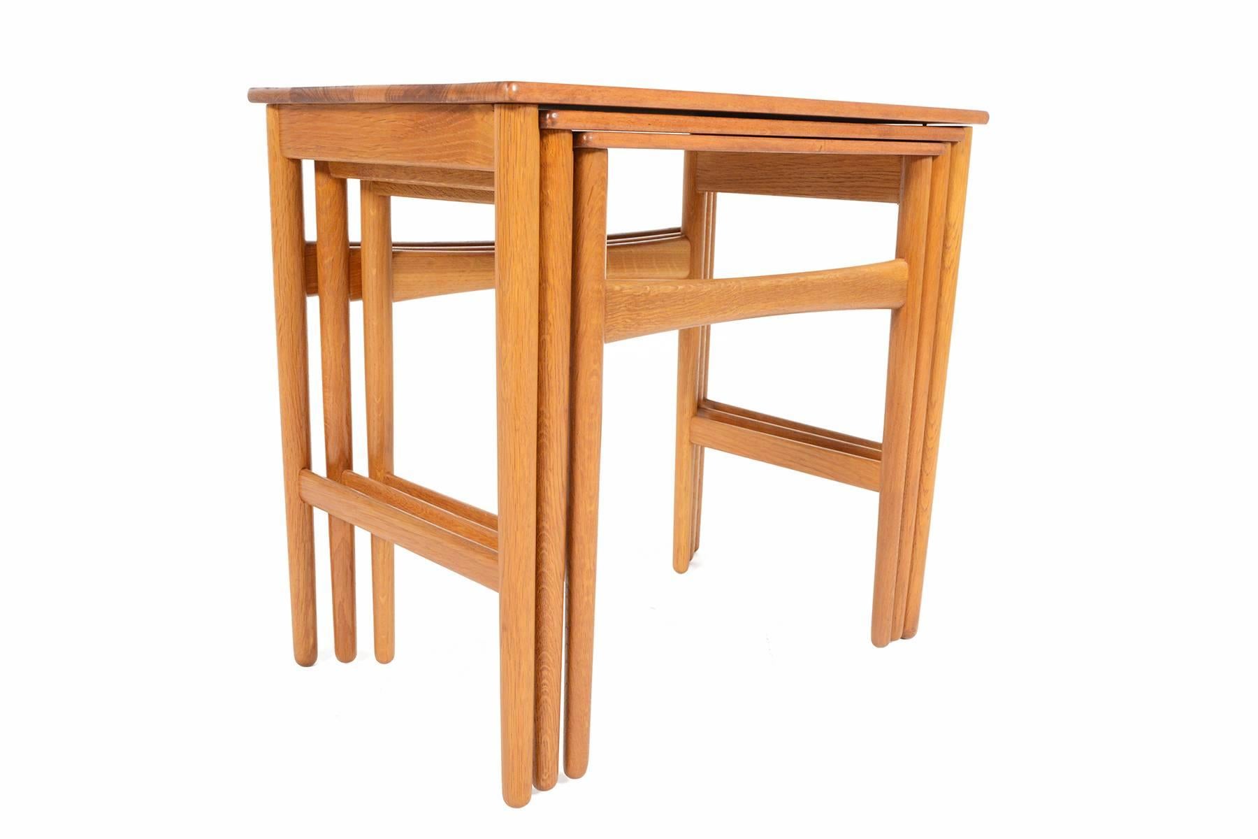 This set of absolutely gorgeous Danish modern nesting tables in teak and oak was designed by Hans Wegner in the 1960s. With old growth, rich grain throughout the solid teak tops, these tables float delicately above braced oak legs. A fantastic