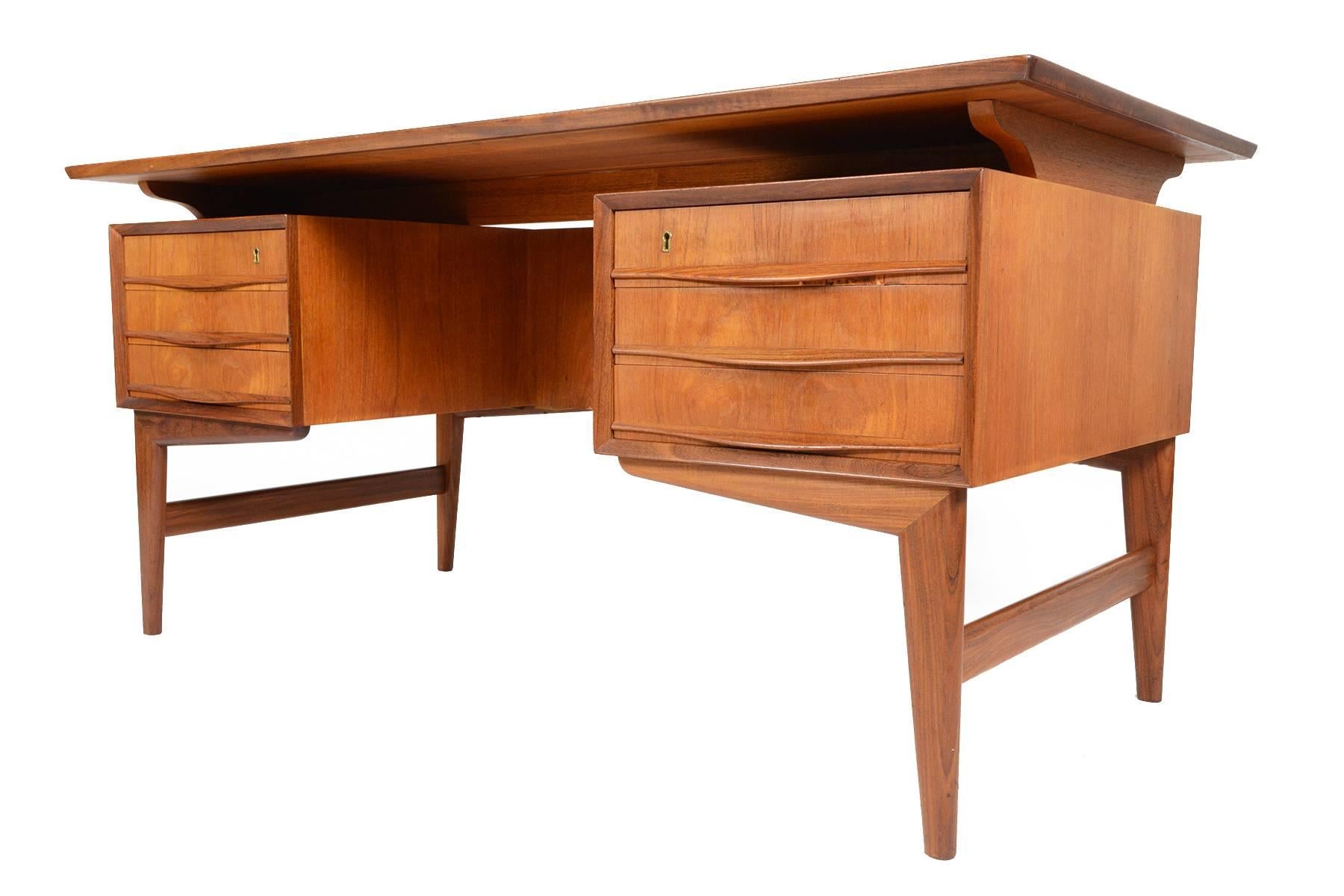 This Danish modern Svend Madsen style floating top desk features a beautifully cornered teak desk surface. Two banks of three drawers sit on either side of the kneehole providing excellent storage. Finished on all sides, this desk can be floated in
