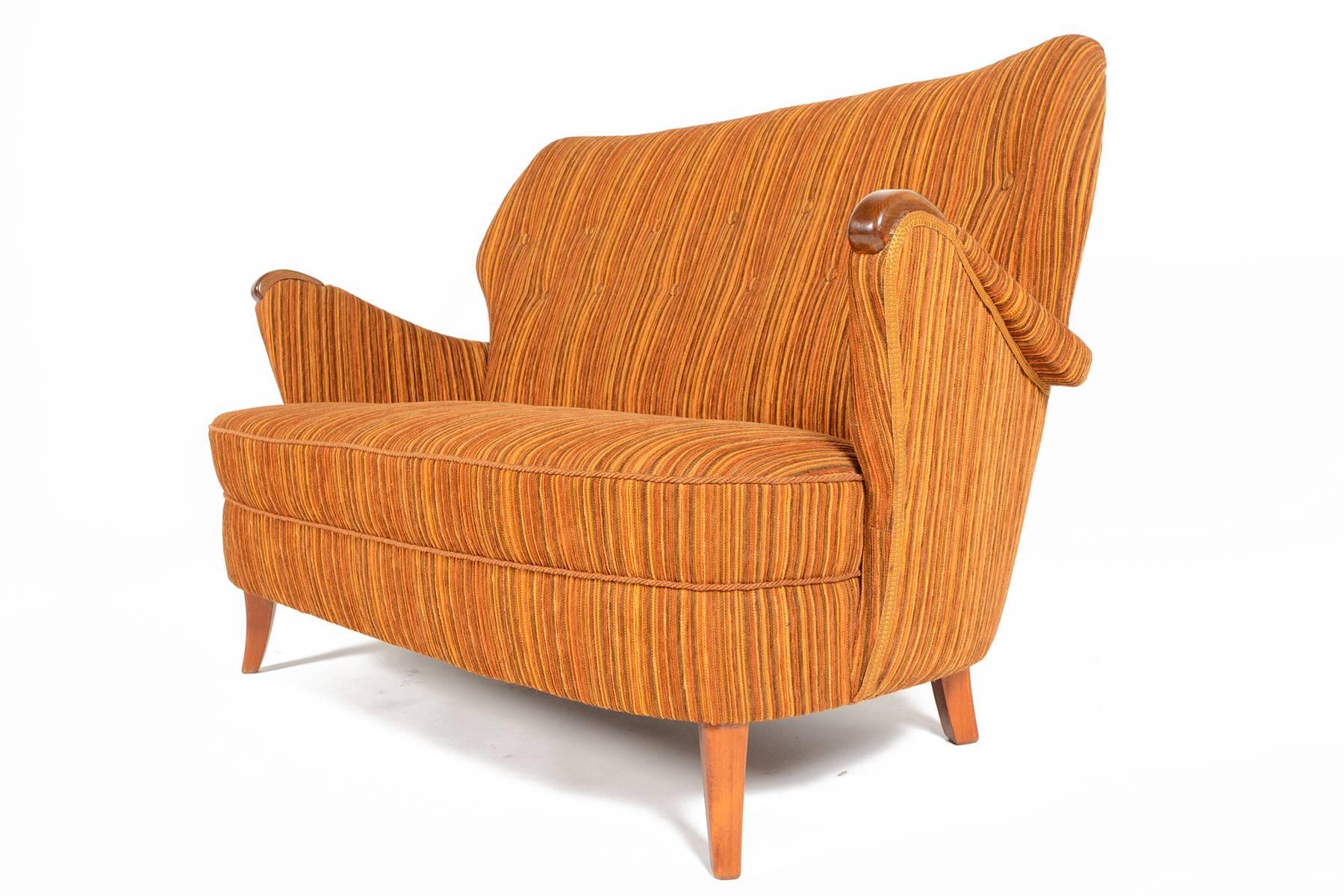 Beautiful and rare, this Swedish sofa will be the perfect addition to any modern room. Comfortably seating two or three, this settee features beautiful curves. Upholstered on all sides in original striped autumn toned corduroy. Cushions and backrest