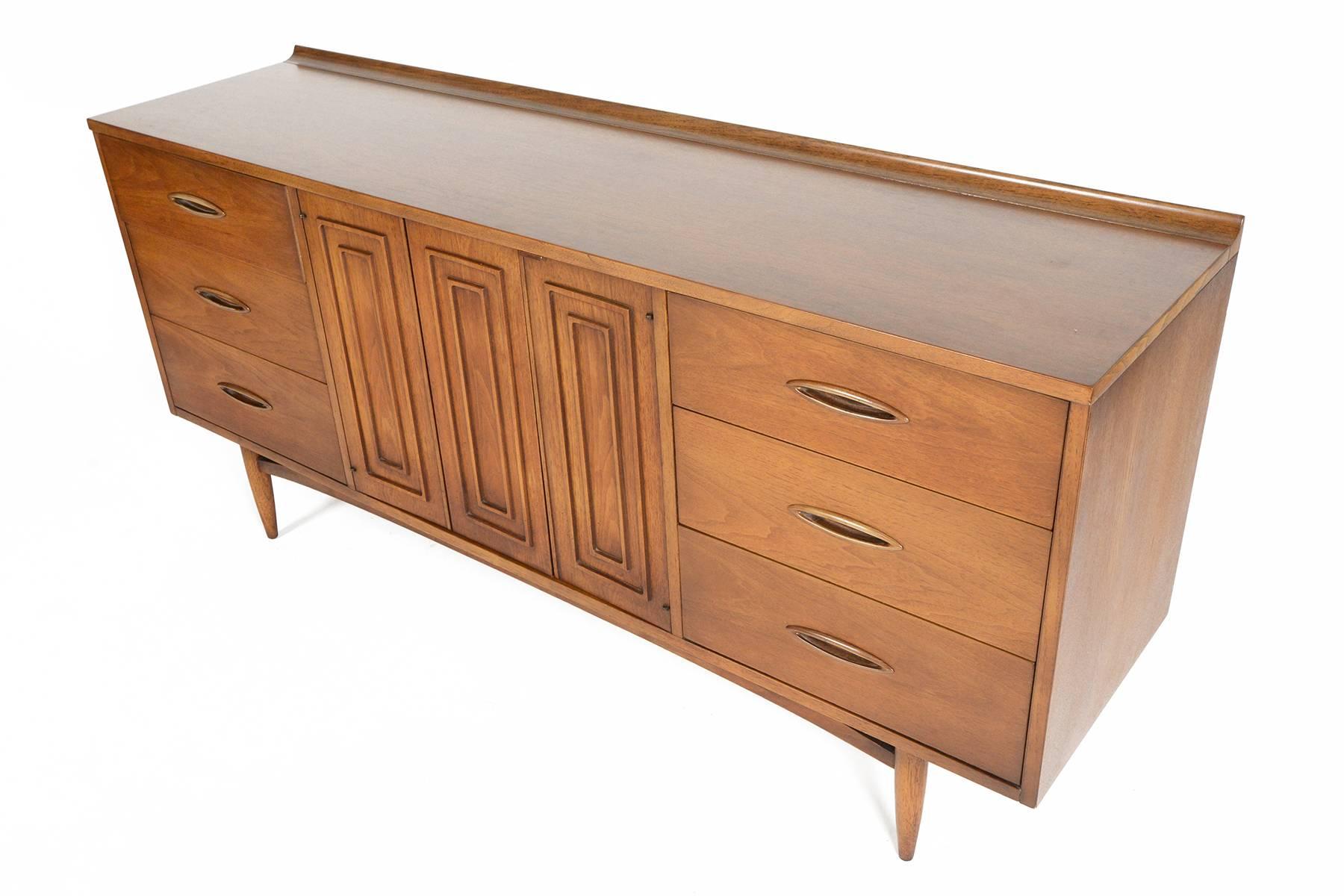 This stunning low nine-drawer dresser was designed and manufactured by Broyhill in 1957 for their extremely successful line of Sculptra furniture. Designed to offer minimal adornment and clean lines, this dresser will work well in any modern home.