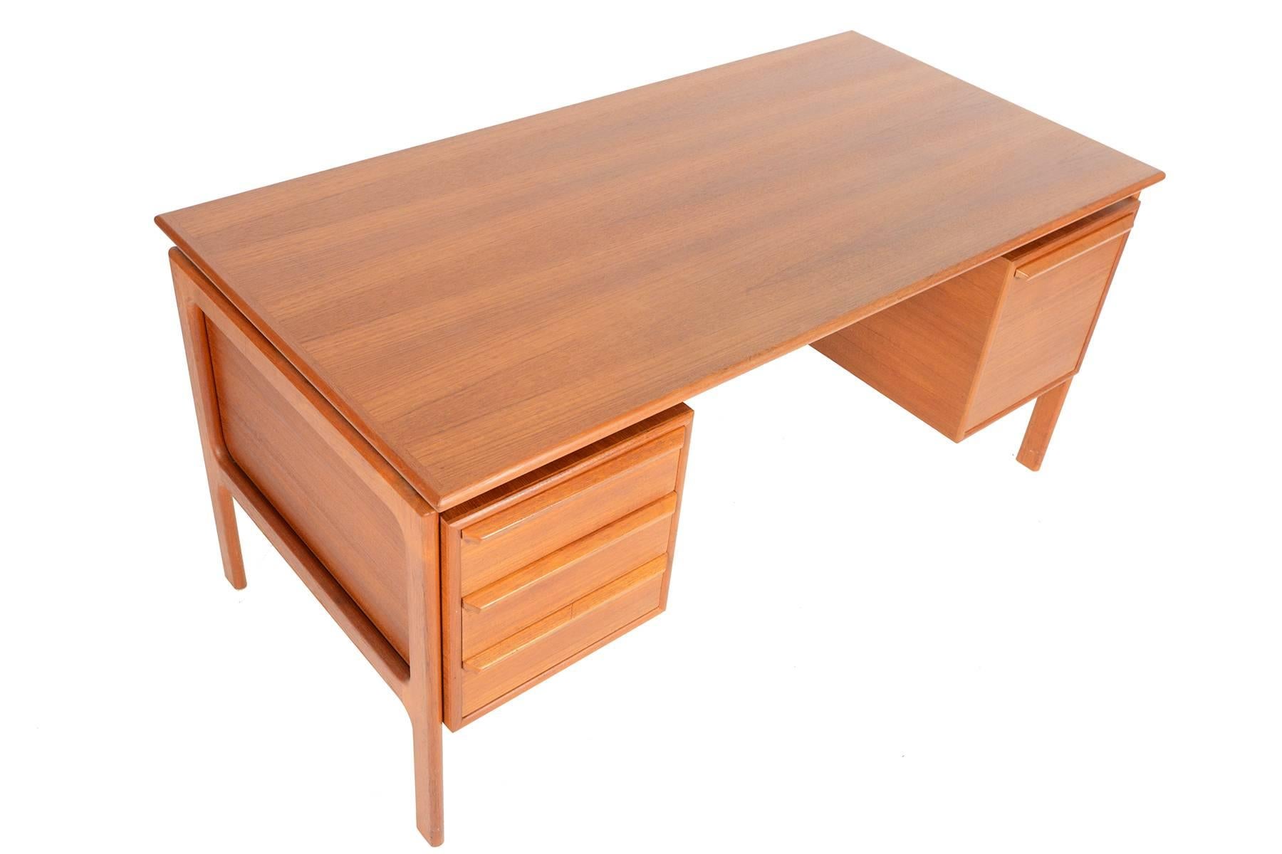 This Danish modern executive desk in teak was manufactured by G. V. Gasvig in the 1960s and offers a large working surface and great storage. Left of the kneehole features three deep drawers while the right cabinet offers a pull-out file
