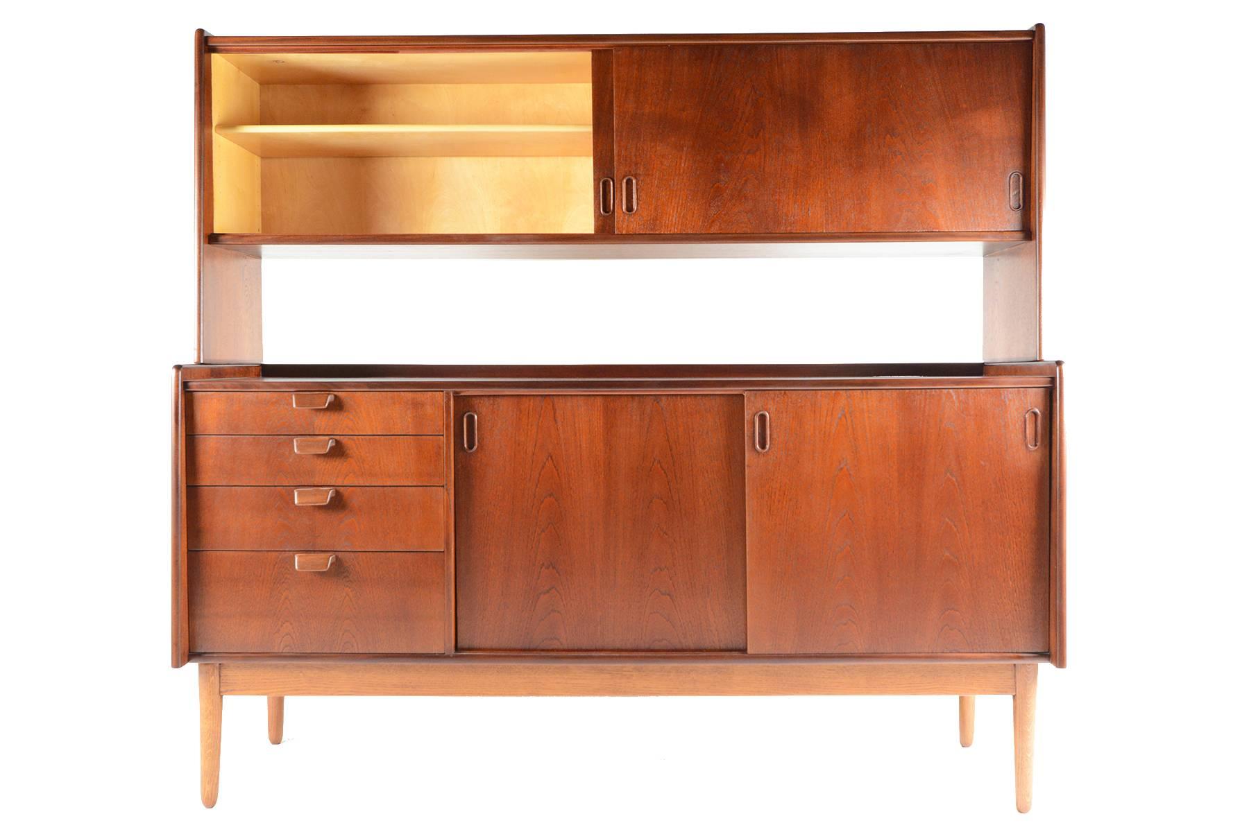 This wonderful modular Danish modern Mid-Century teak credenza with hutch is the perfect versatile piece for any modern home. The credenza supports a teak sliding door hutch with two bays and adjustable shelves. Lower credenza features two sliding