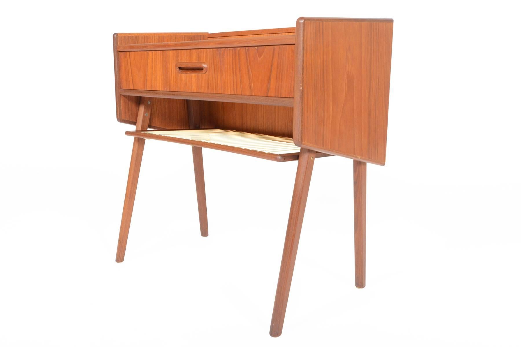 This gorgeous Danish modern Mid-Century V-legged entry chest will make a great addition to any modern home. Crafted in teak, this piece features a shelved top with centrally located drawer for storage. A lower rack provides additional storage. In