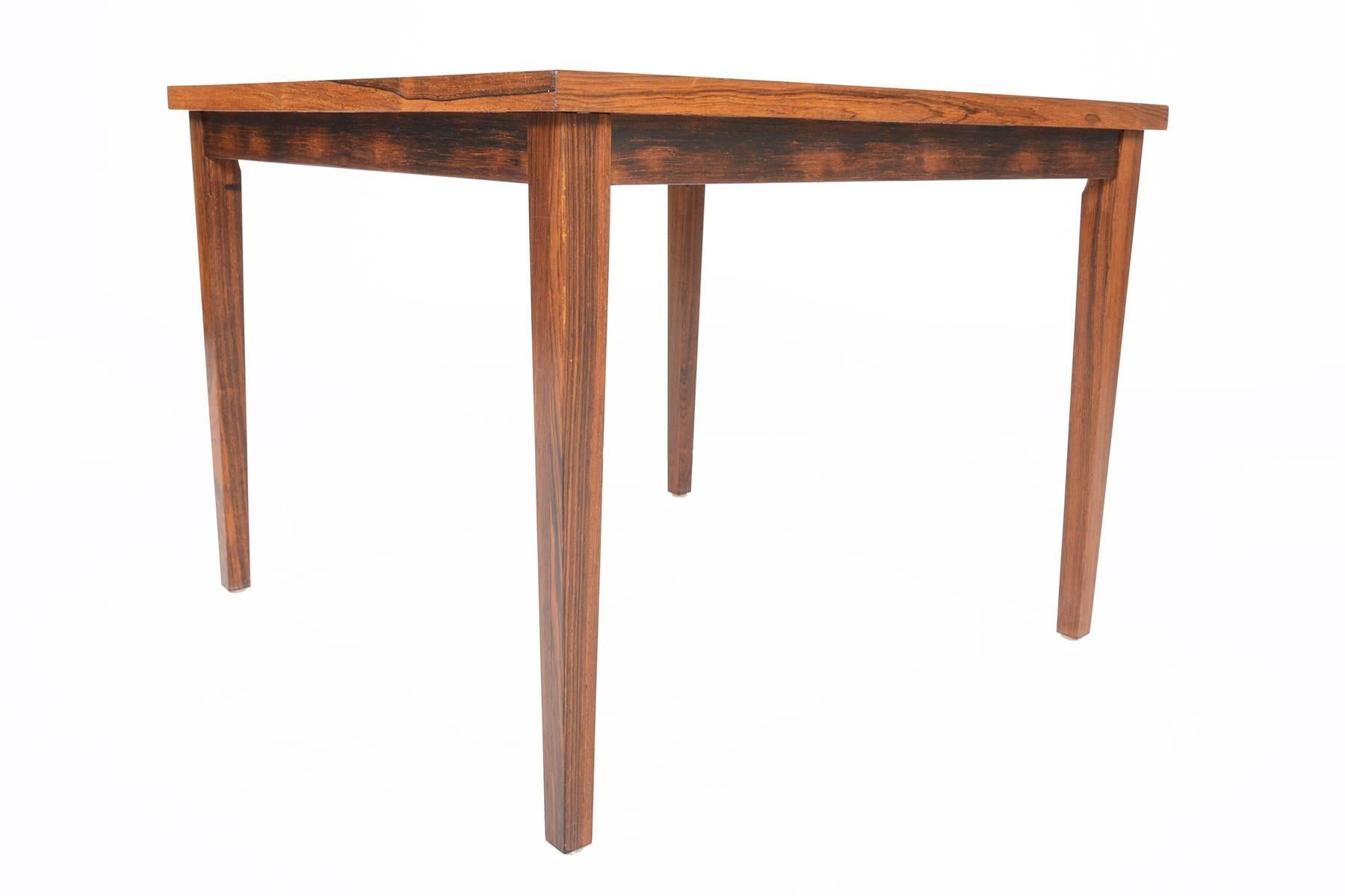 This lovely Danish modern Mid-Century square slatted coffee table features beautiful rosewood grain in a simple yet elegant form. Raised on tapered square legs, this piece will provide elegance and sophistication to any home. In excellent original
