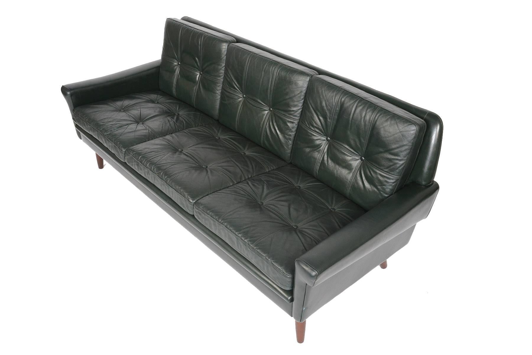 This Danish Modern Mid-Century svend skipper for Skipper Møbelfabrik three-seat sofa in dark green leather hails from the 1960s and will blend perfectly with any modern decor. The frame holds six cushions, each featuring a linear double stitch