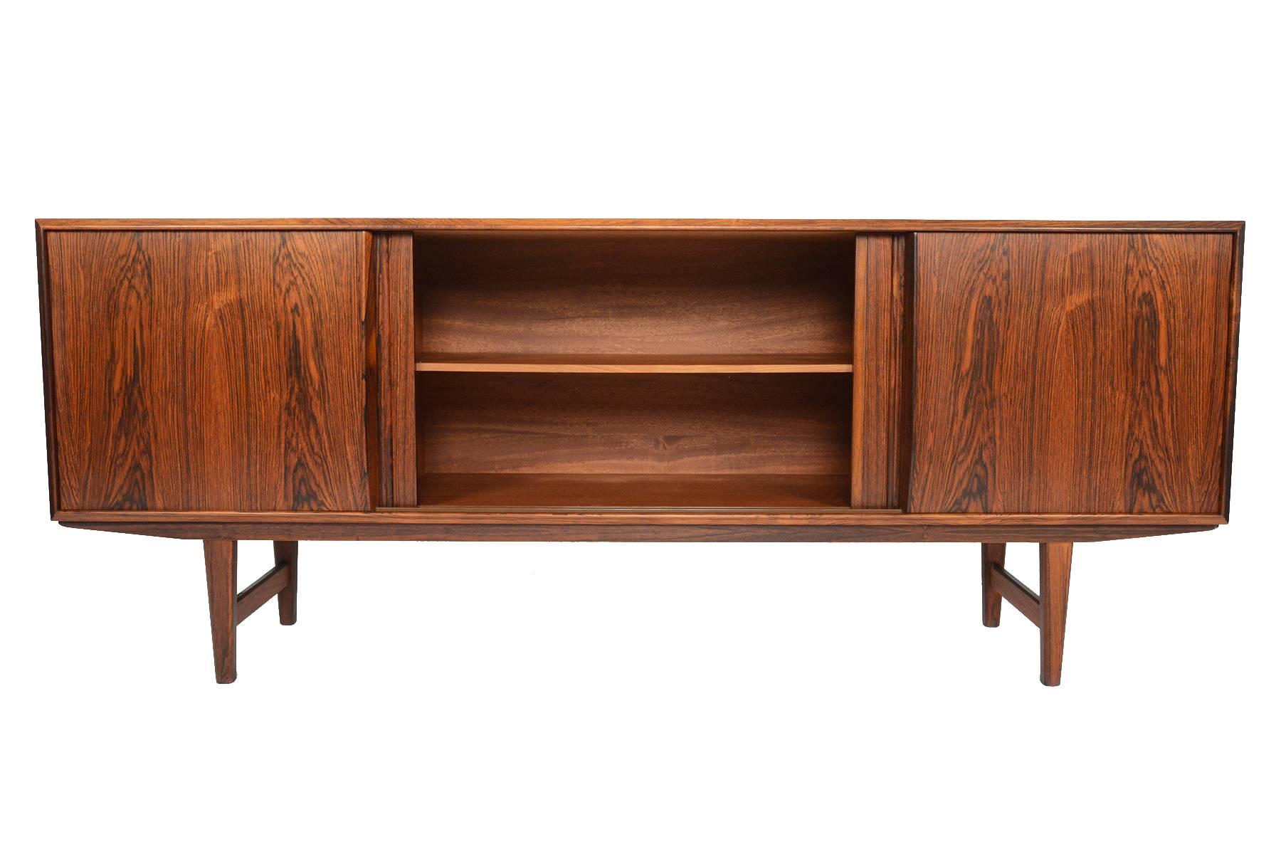 This Danish modern Mid-Century credenza in rosewood was designed by E.W. Bach for Sejling Skabe. With smoothly sliding doors accented by hand-carved pulls, this is a great storage solution for any modern home. All bays feature adjustable shelves and
