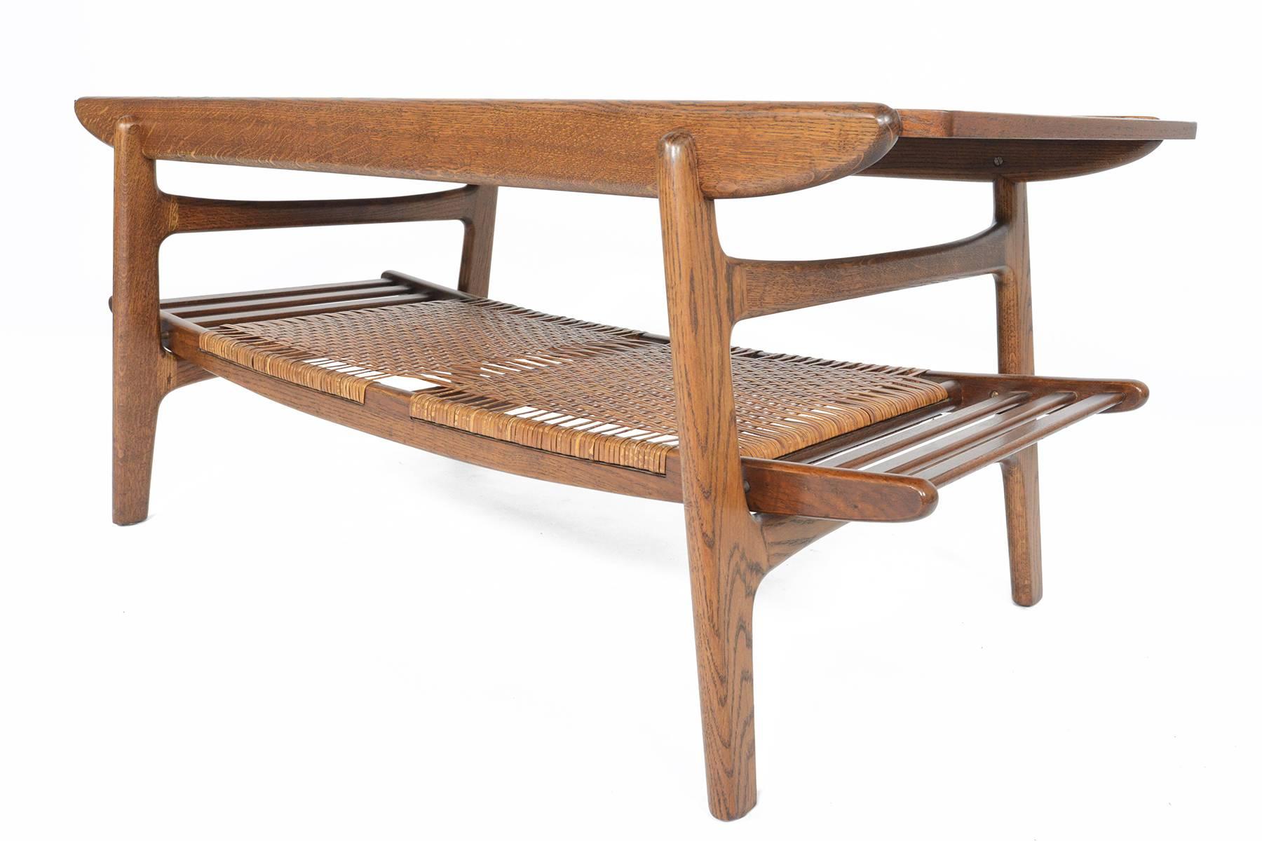 This Danish modern Mid-Century surfboard coffee table in teak and oak is the statement piece your living room has been waiting for! A gorgeous teak slab is nestled in a quarter, sawn oak frame. An original cane rack offers a wonderful storage