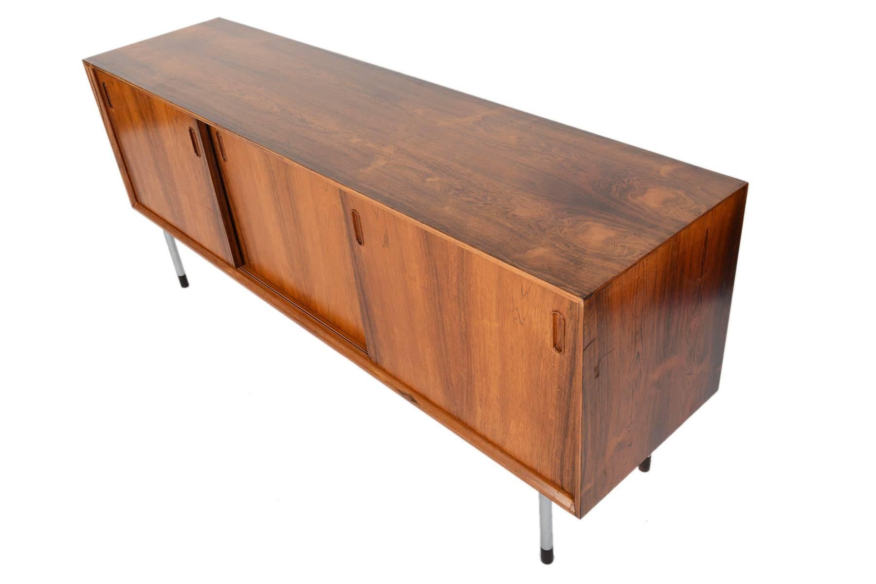 This Danish modern credenza hails from the 1960s and is perfectly sized for modern living. Crafted in Brazilian rosewood with handsomely refined lines, the three sliding doors open to reveal three bays with adjustable shelving and seven drawers in