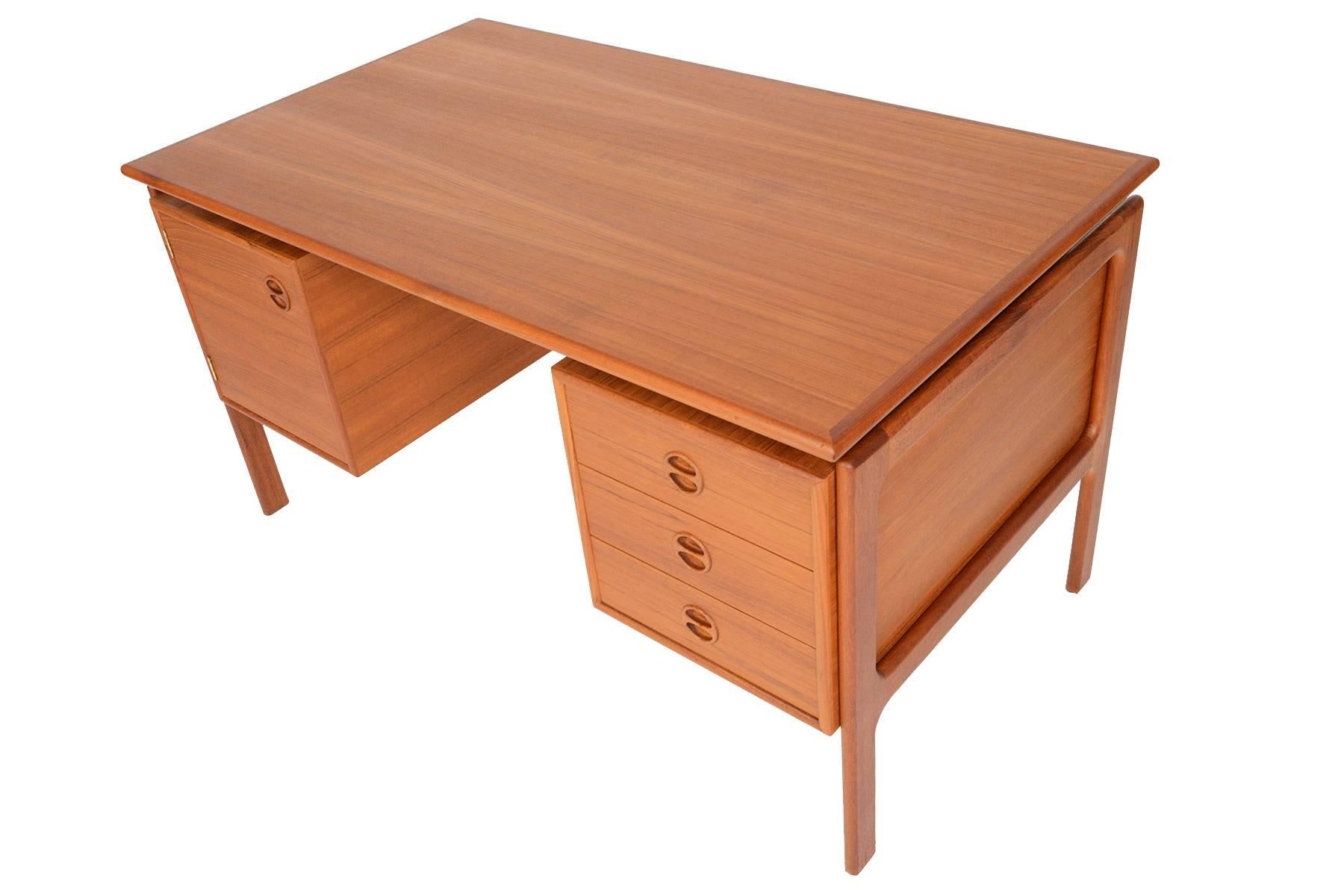This Danish modern executive desk in teak was manufactured by G. V. Gasvig in the 1960s and offers a large working surface and great storage. Left of the kneehole features a large cabinet while the right cabinet offers three deep drawers. Carved