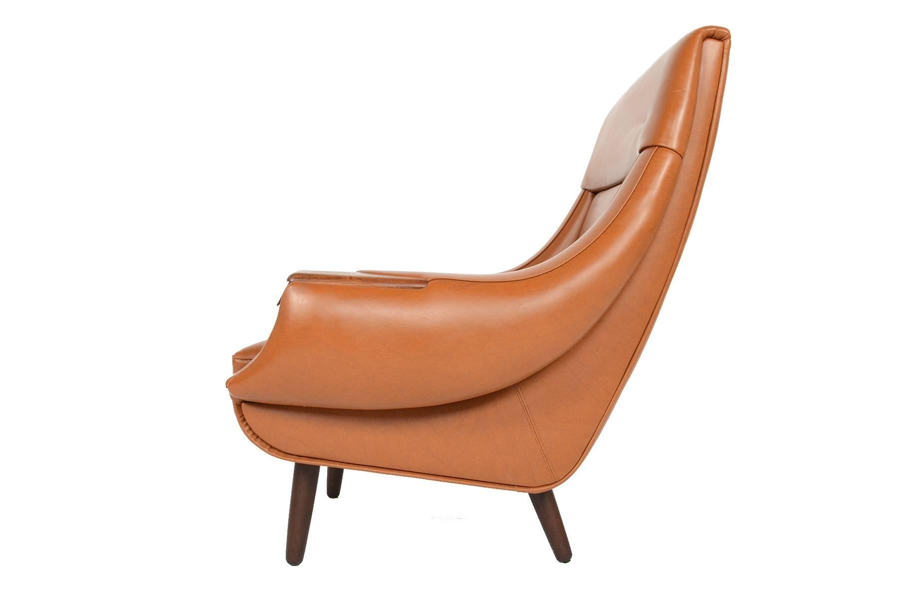 Late 1960s Scandinavian design is on full display with this gorgeous highback lounge chair designed by H.W. Klein for Bramin. Cascading arms and a wide, contoured base give the feeling of movement to this design. Two carved rosewood pulls sit on the