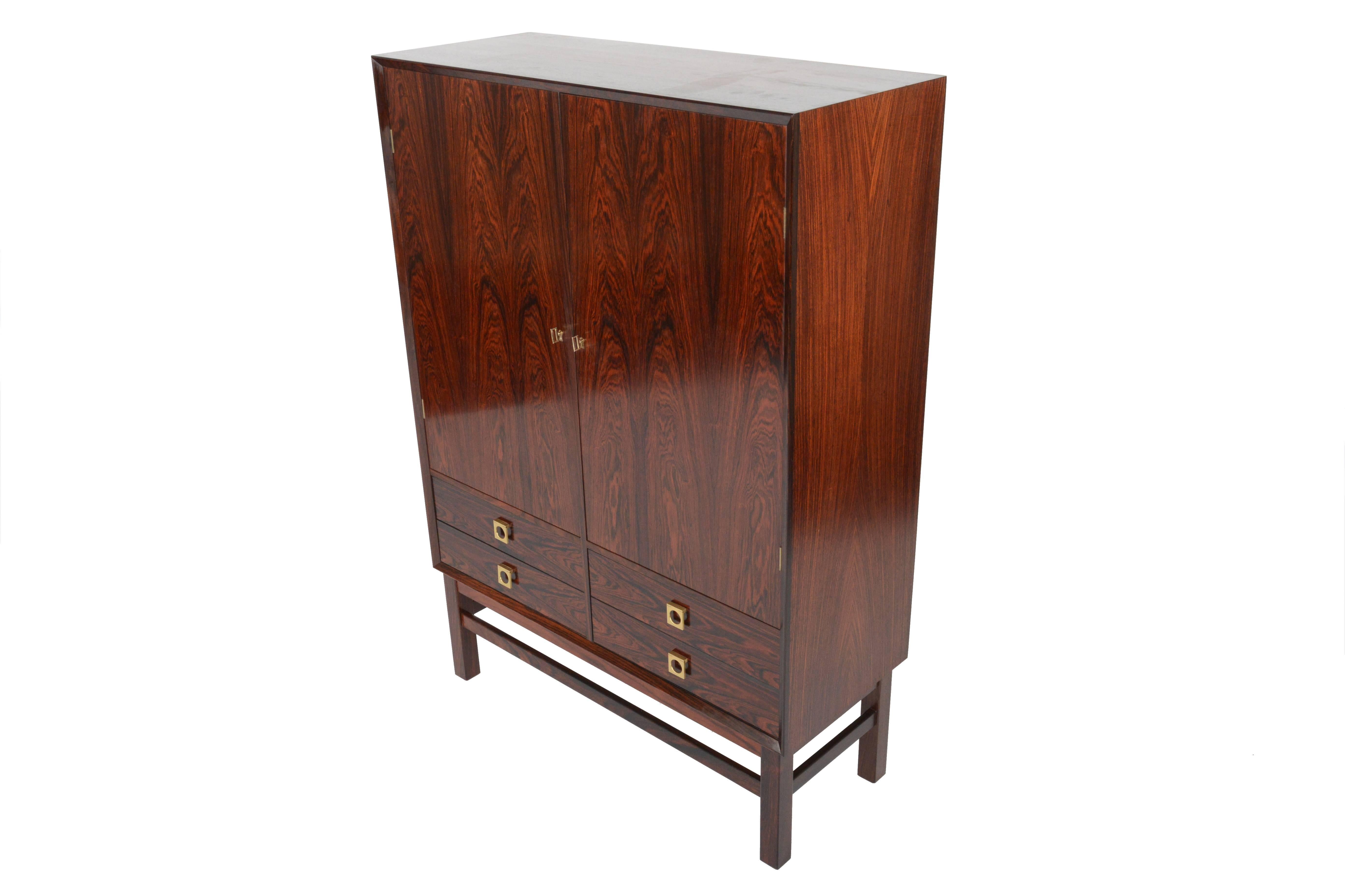 This fantastic Danish modern tall credenza by Brouer Møbelfabrik offers fantastic rosewood wood grain and superior craftsmanship throughout! Two locking doors open to reveal two bays with adjustable shelving. Four lower drawers provide additional