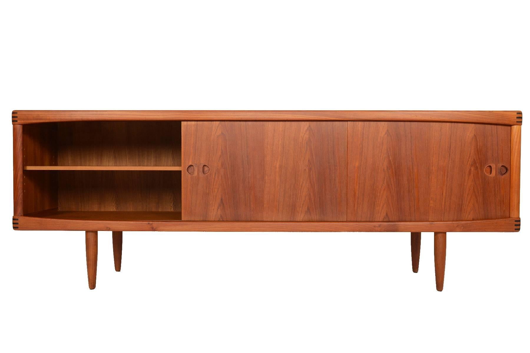 This breathtaking Danish modern teak credenza was designed by H.W. Klein and manufactured by Bramin in the 1960s. Left and right doors slide open to reveal adjustable shelving. Four centre drawers provide additional storage. All doors and drawers