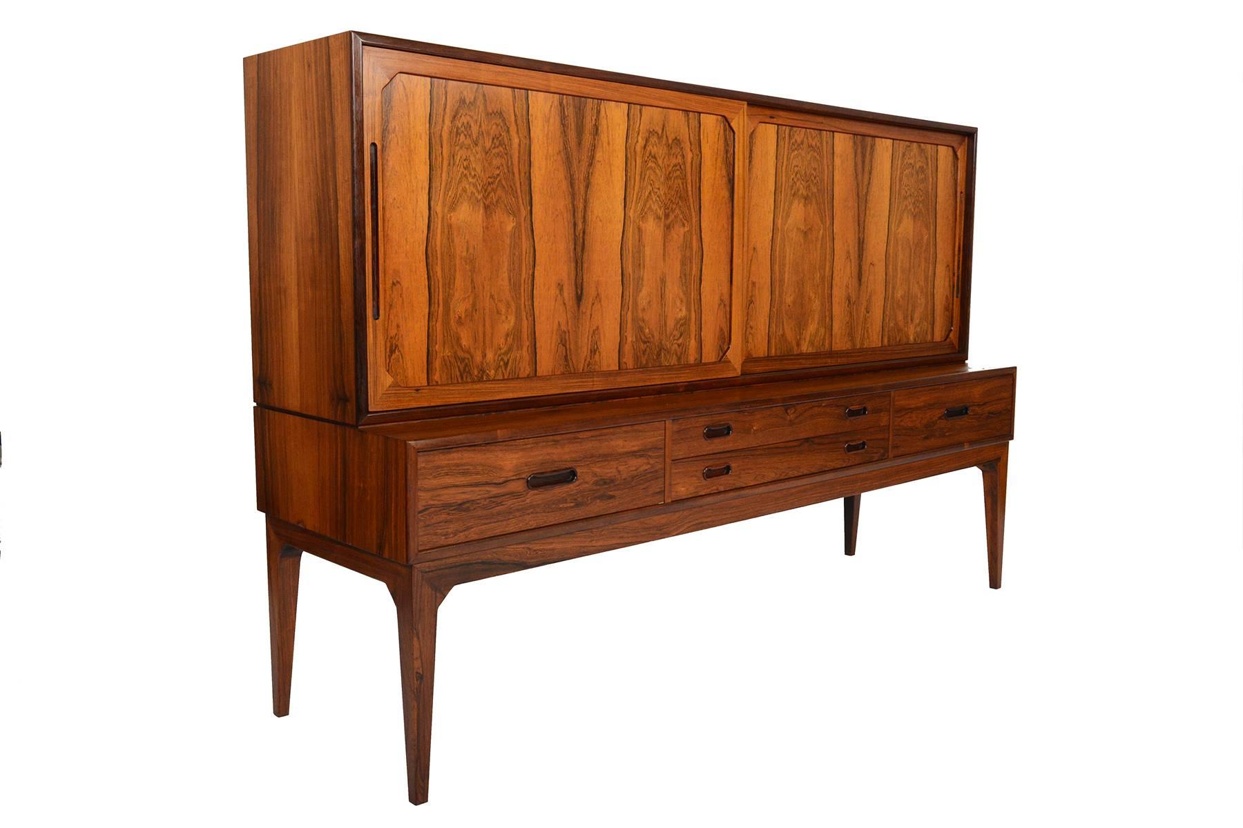 Manufactured by Schou Andersen in the 1960s, this beautiful and unique Danish modern Brazilian rosewood credenza features sculpted framed inlays on each door. Left and right doors open to reveal three bays with a series of adjustable shelves and