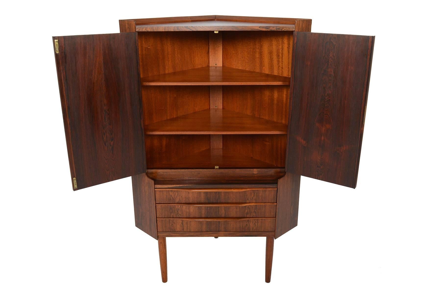 This Danish modern Mid-Century corner cabinet and bar is perfect for any space with limited storage. Crafted in Brazilian rosewood, this piece will tuck easily into any corner of your home, providing you with a ready to use dry bar. Two top locking