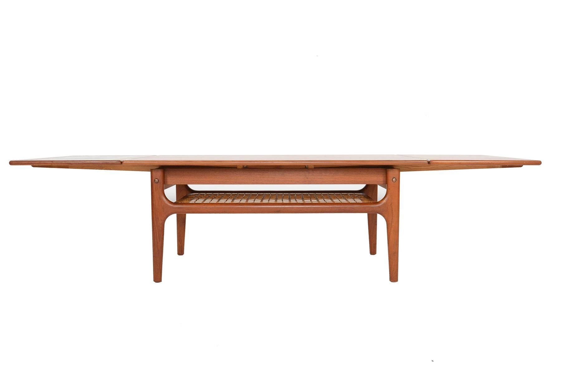 This Danish modern Mid-Century surfboard coffee table in teak by Trioh is beautifully designed. The rectangular teak slab features a softly sculpted lip. Two leaves extend from underneath the table. One leaf features an original laminate lined