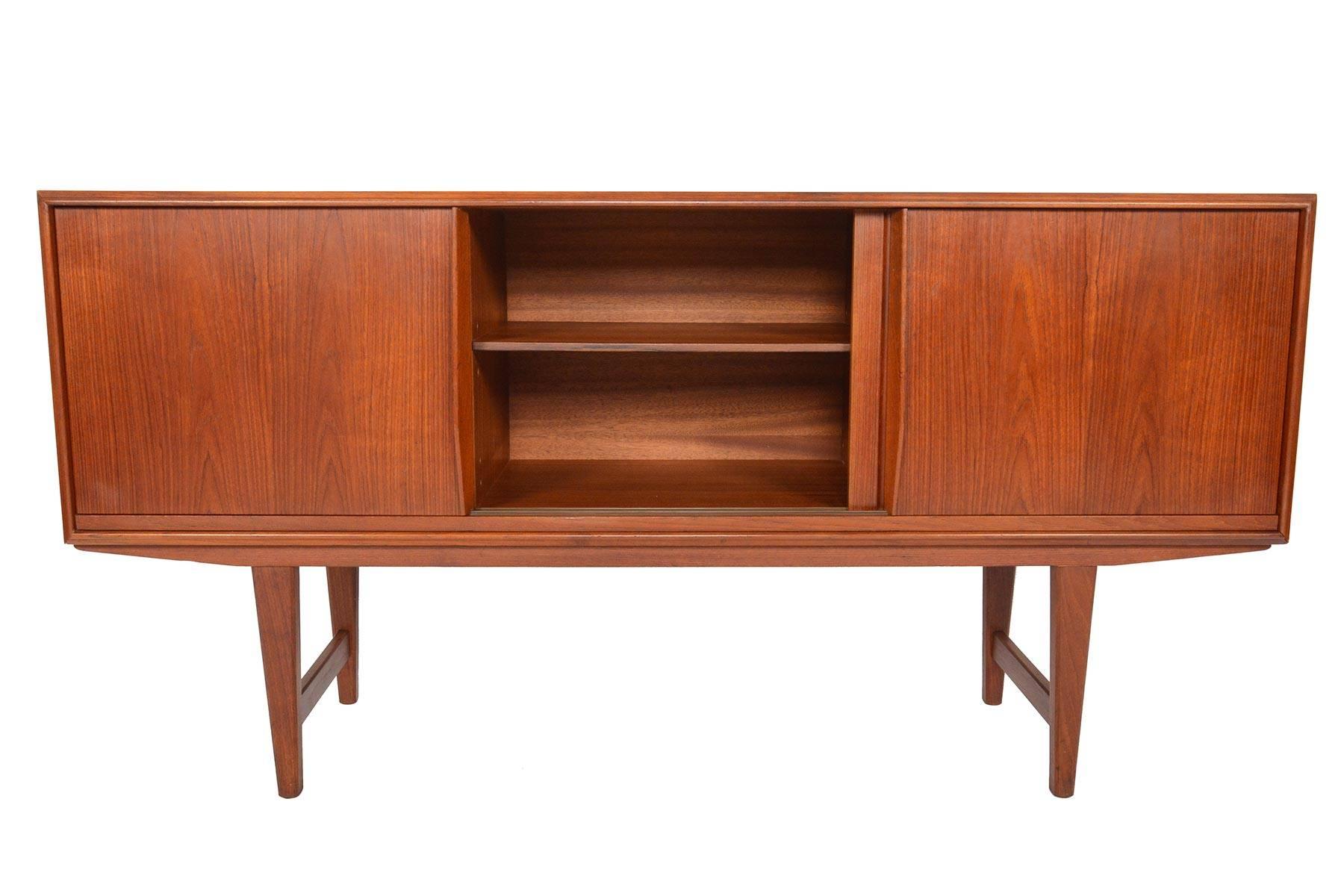 This Danish modern credenza in teak was designed by E.W. Bach for Sejling Skabe. With smoothly sliding doors accented by hand-carved pulls, this is a great storage solution for any modern home. Left and center bays offer adjustable shelves and the