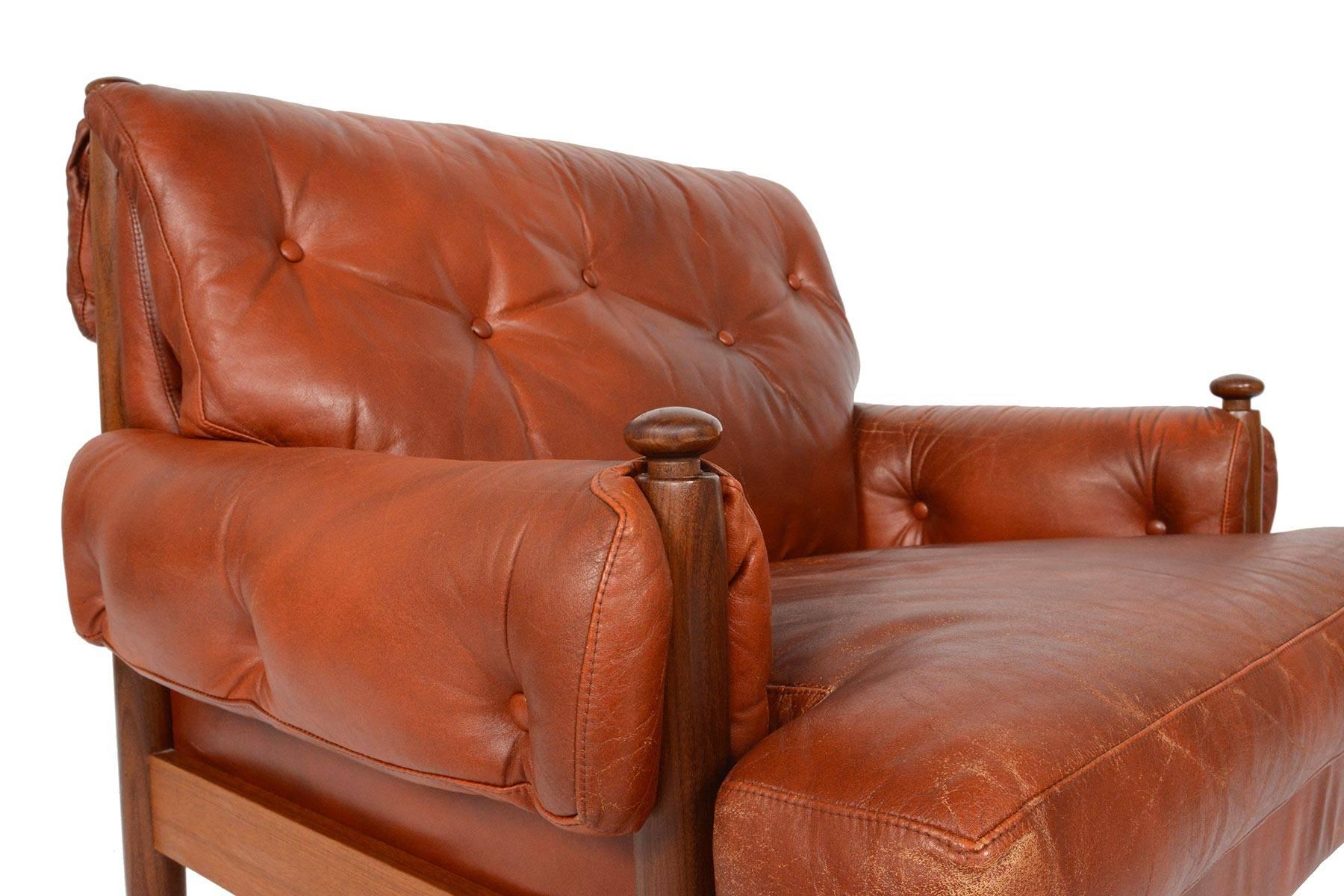 This Swedish modern leather club chair is as cozy and comfortable as they come! With a Silhouette reminiscent of Sergio Rodrigues' Sheriff chair, this solid walnut frame holds original rust red leather cushions. The cushions fold over the sides of