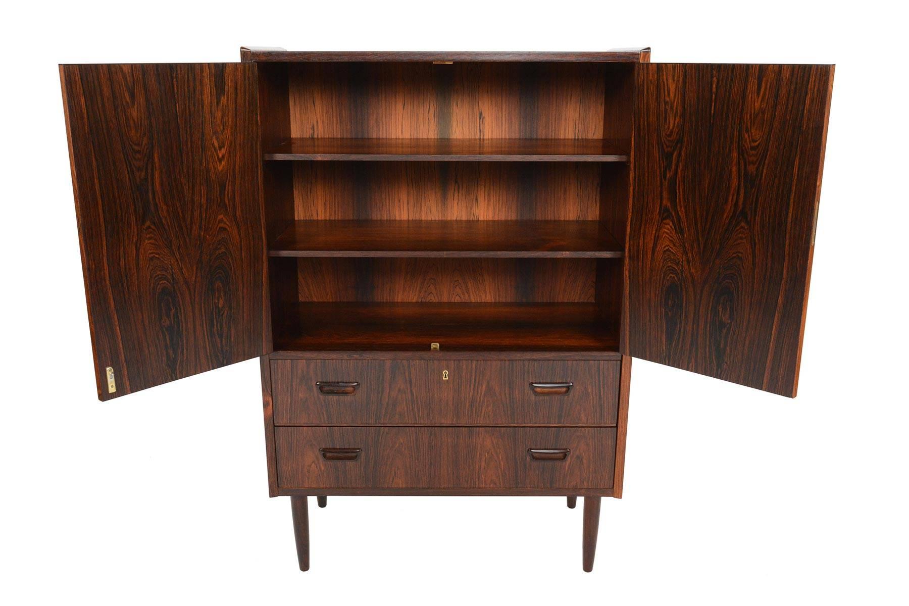This stunning Danish modern bureau in Brazilian rosewood offers exceptional storage for any room! Perfect for use as a dresser, bookcase, or bar! Two large locking doors open to reveal a spacious interior with adjustable shelving. Two lower drawers