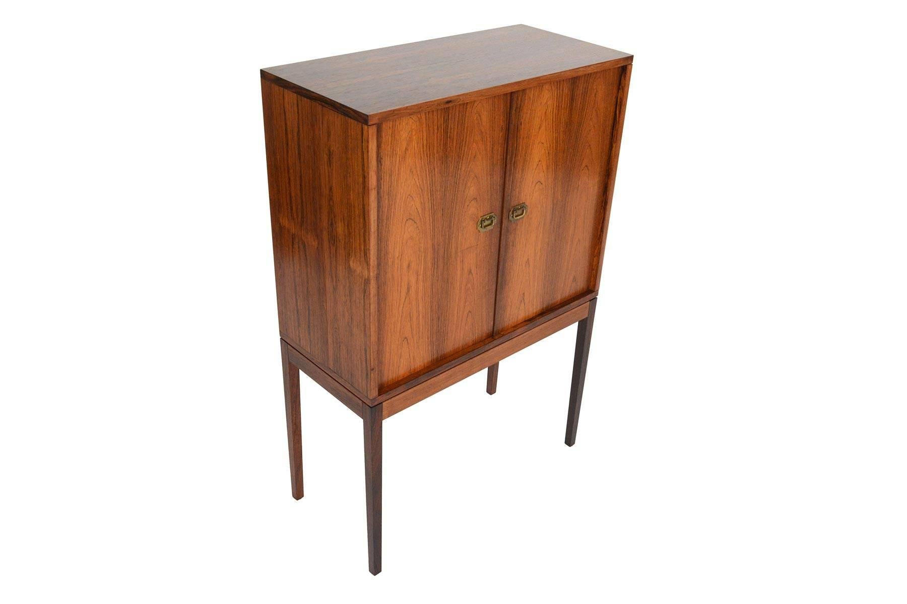 This beautiful small Danish modern bar was designed by Henning Korch in 1968 for Silkeborg Møbelfabrik as model 132. Two doors with the designer's signature brass pulls open to reveal an adjustable glass shelf. Both doors feature three deep shelves