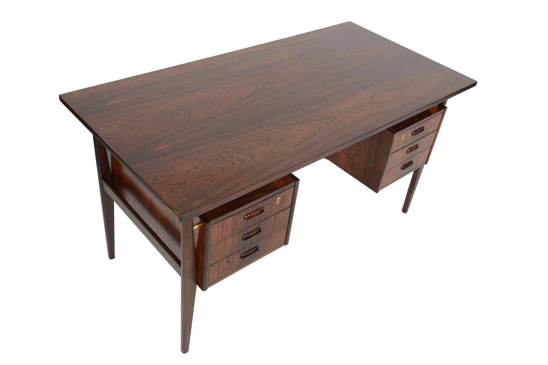This Danish modern floating top desk in Brazilian rosewood is the perfect piece for any modern office! The kneehole is nestled between two banks of three drawers. Each drawer offers an Arne Vodder style pull. Finished back features two open storage