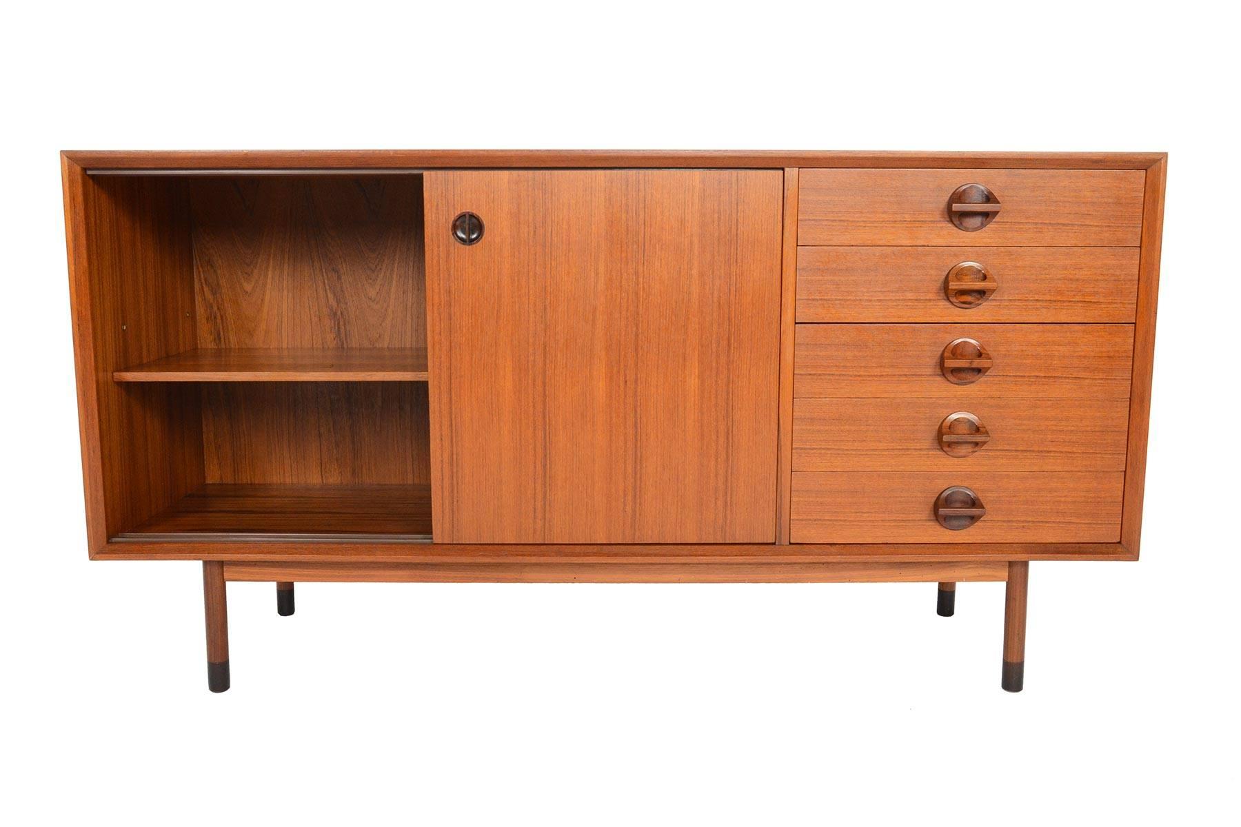 This astounding Italian Mid-Century Modern credenza by Faram is an absolute favourite. Two large teak sliding doors open to reveal an adjustable shelf. A bank of five drawers sits to the left. Doors and drawers are adorned with simply stunning