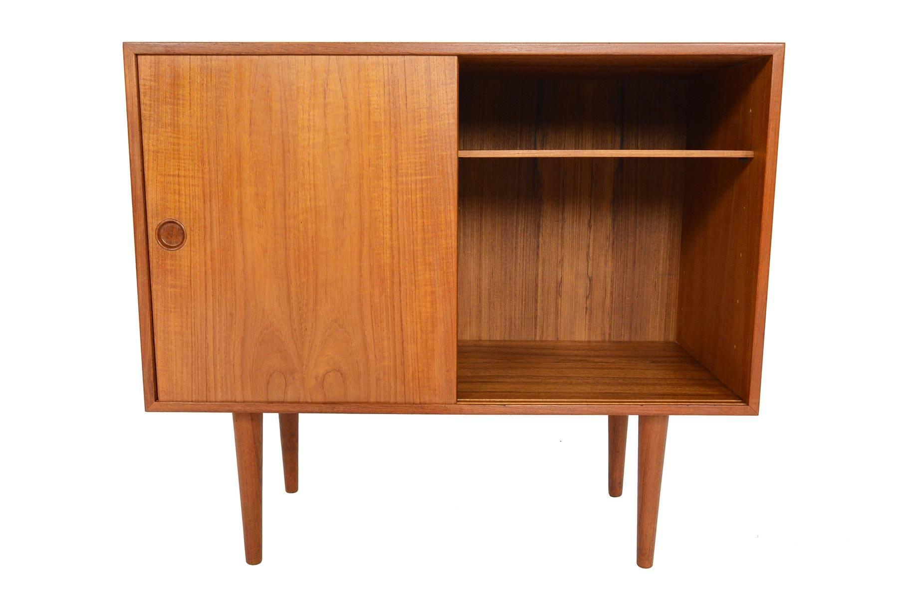 This beautiful small two-door credenza in teak was designed by Kai Kristiansen for Feldballes Møbelfabrik in the 1960s. Two sliding doors open to reveal two bays with an adjustable shelf on the right and a felt lined birch flatware drawer on the