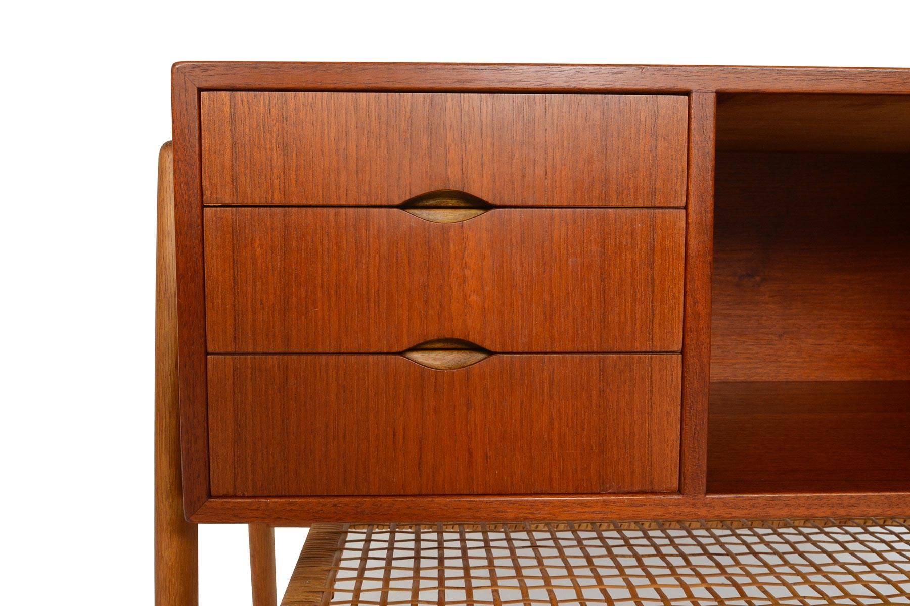 This Danish modern midcentury atomic teak and oak entry chest with caned rack is a perfect specimen of Scandinavian design. The expertly built teak case is flanked by sculpted quarter-sawn oak legs. Three drawers sit to the left of the case and