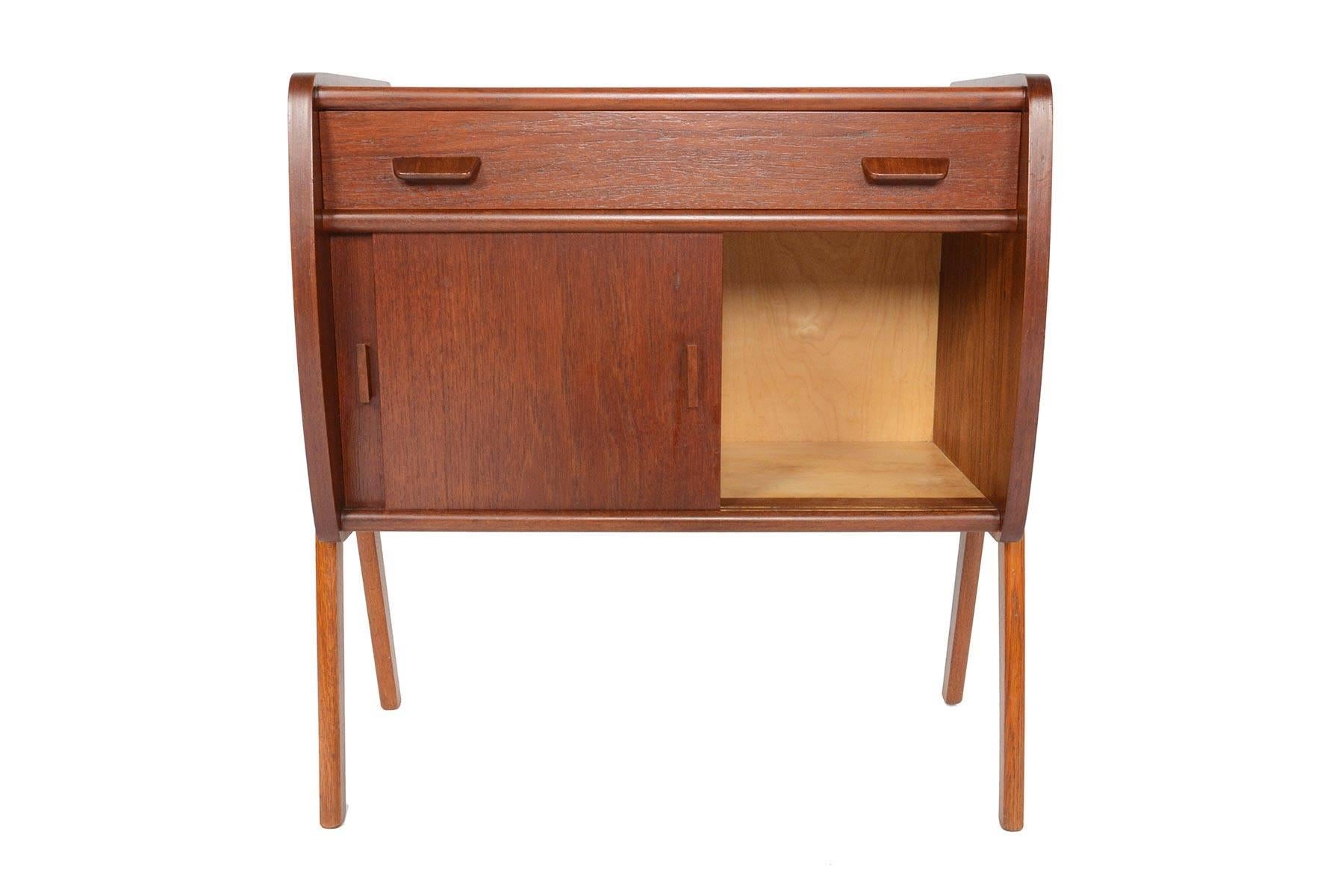 This gorgeous Danish modern midcentury V-legged entry chest will make a great addition to any modern room or entry way. Crafted in teak, the case provides a drawer and a spacious oak- lined interior accessible by sliding doors. Piece stands on solid