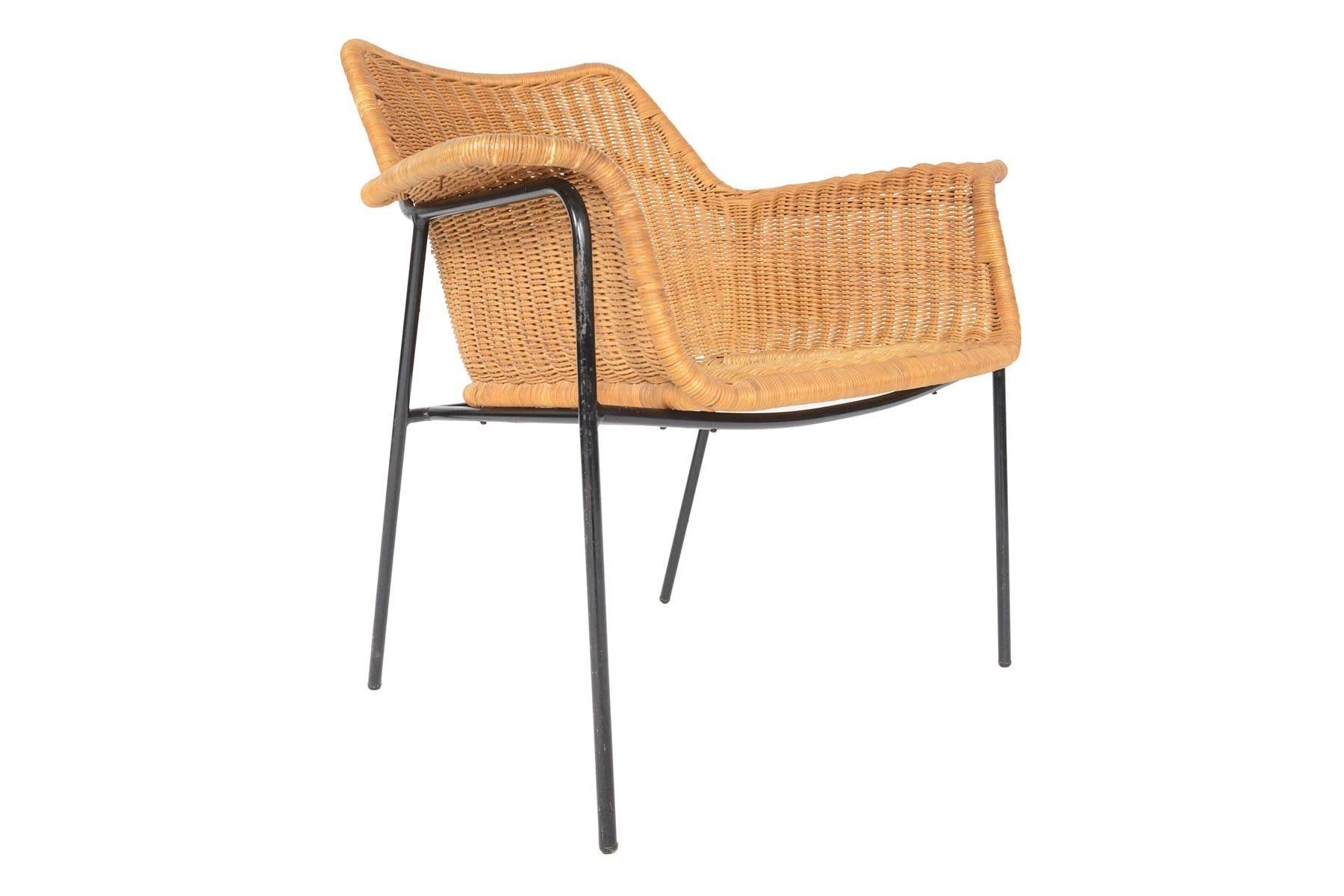 This unusual Danish modern lounge chair is crafted in wicker and iron and offers wonderful midcentury stylings. The wicker bucket features winged arms which delicately lay over the ebonized iron frame. In excellent original condition with typical
