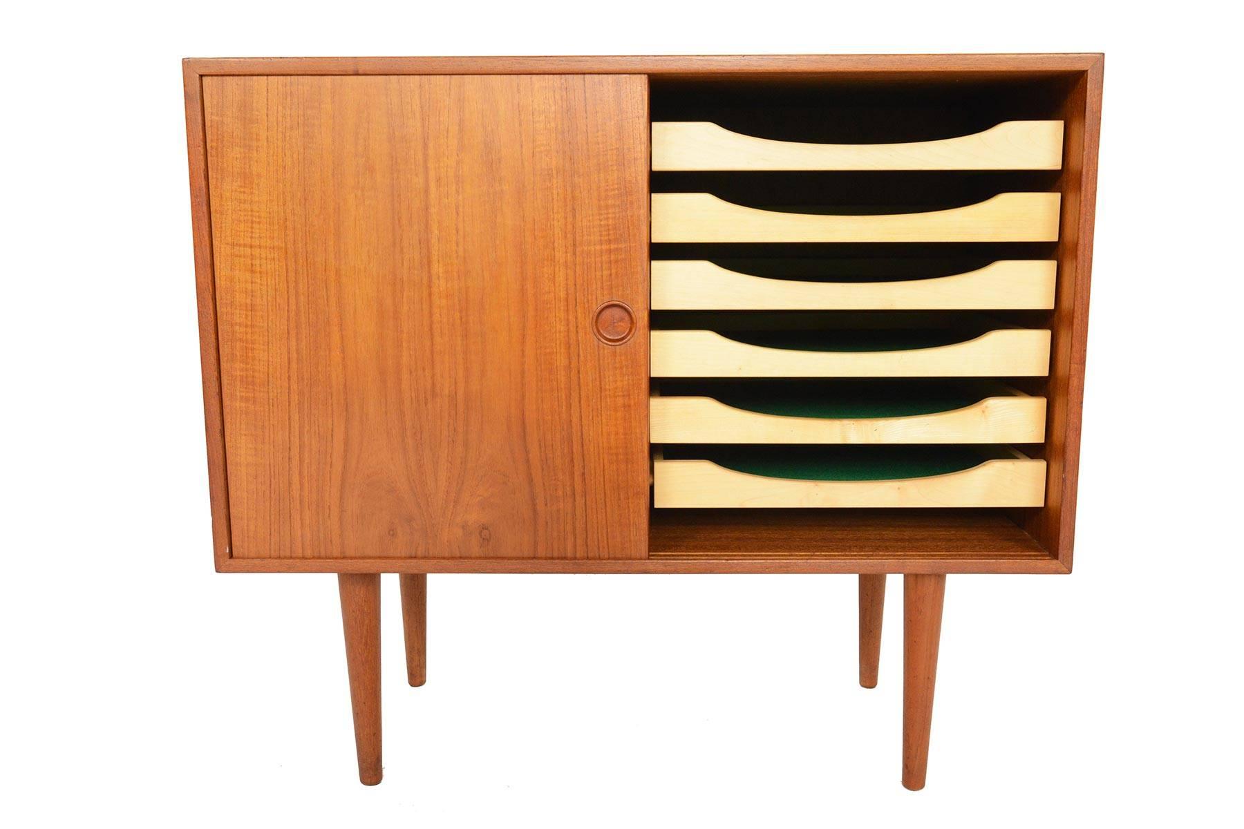 This beautiful small two-door credenza in teak was designed by Kai Kristiansen for Feldballes Møbelfabrik in the 1960s. Two sliding doors open to reveal two bays with three adjustable shelves on the right and six birch flatware drawers on the left.