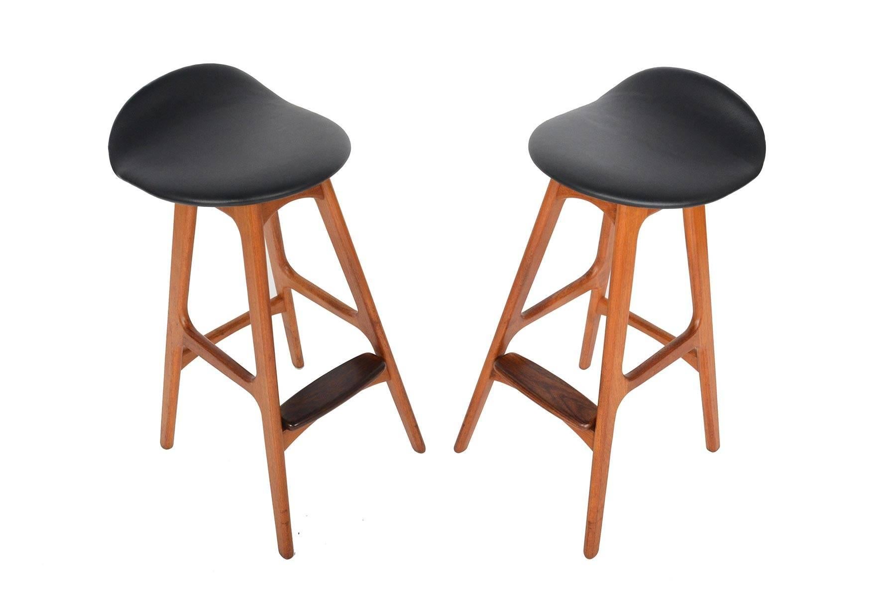 This pair of Danish modern teak bar stools was designed by Erik Buck for Oddense Maskinsnedkeri in 1961. Sitting atop slender tapered legs, this set is sophisticated and sturdy. Exceptional joinery throughout compliments the molded seat designed