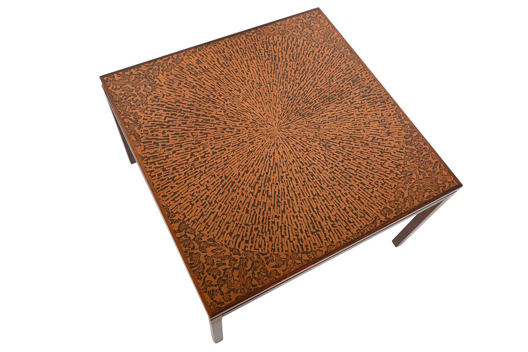 This Danish modern square coffee table in rosewood and copper offers a stunning starburst pattern. Routed banding is complemented with four square tapered legs. In excellent original condition with typical wear for its vintage.

