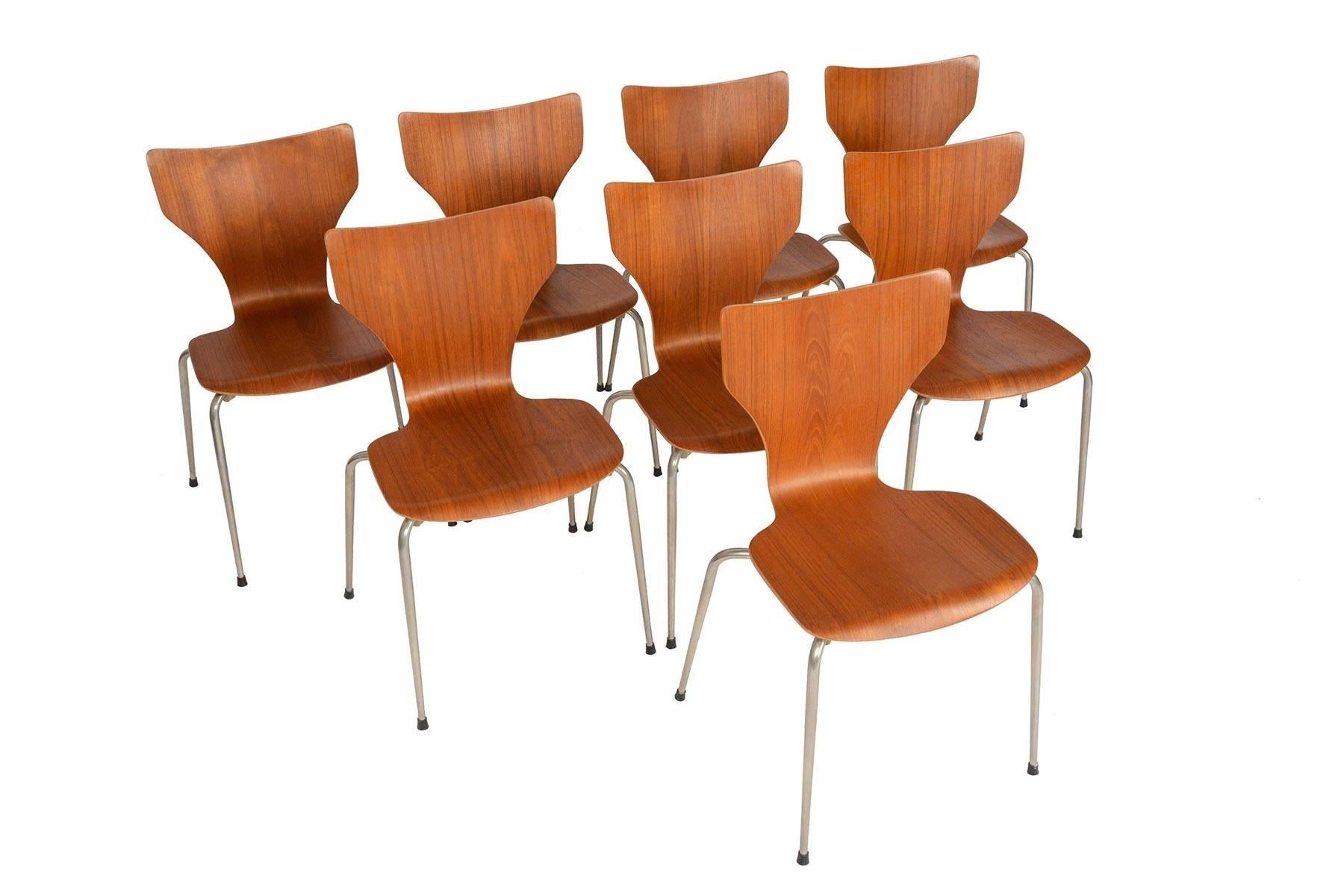 This set of eight Danish modern dining chairs in teak is a quintessential staple of Scandinavian design offering a light, stackable chair with an ergonomic form. The bent ply frame is veneered in teak and features a metal x- form base. In excellent