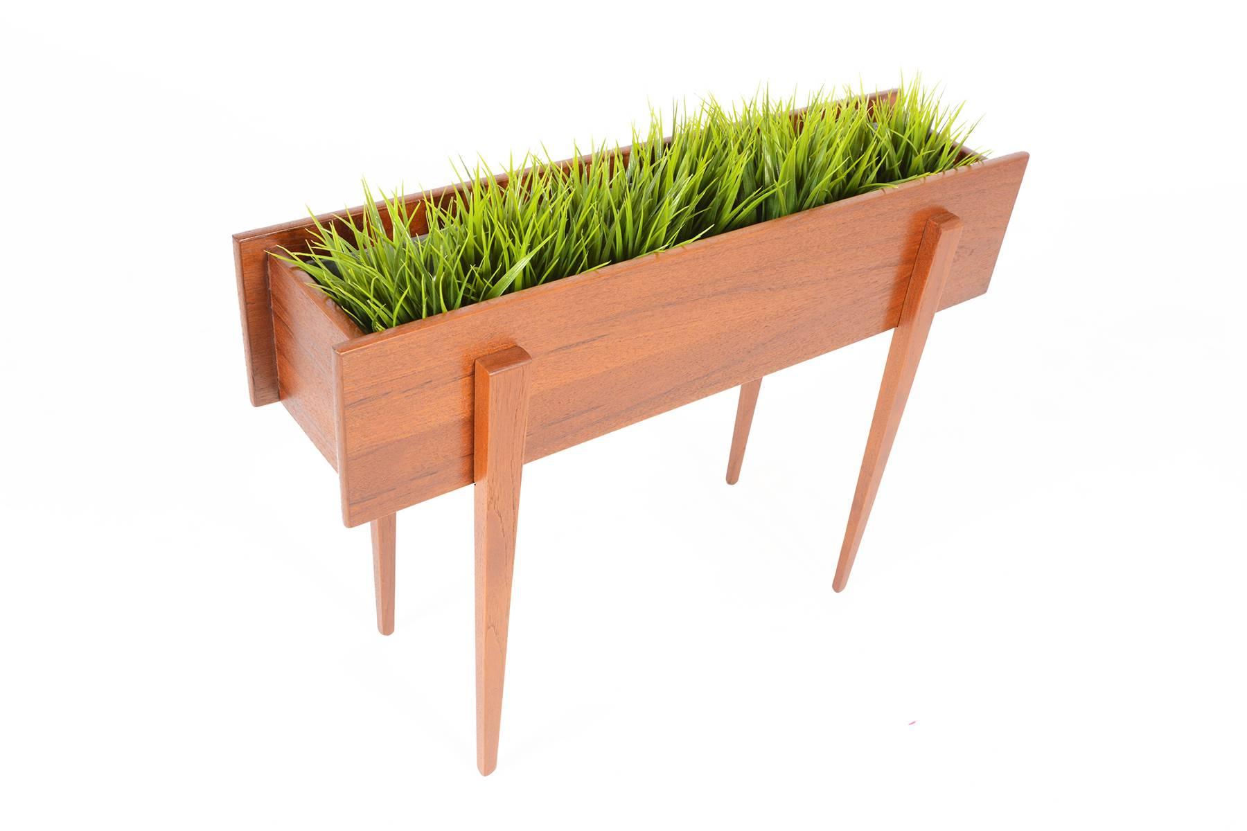 Make your other houseplants jealous of what you display in this amazing Danish modern atomic mid century teak planter box. Exposed legs and angular joinery make this planter a stunner from every angle. A metal liner is removable for cleaning.