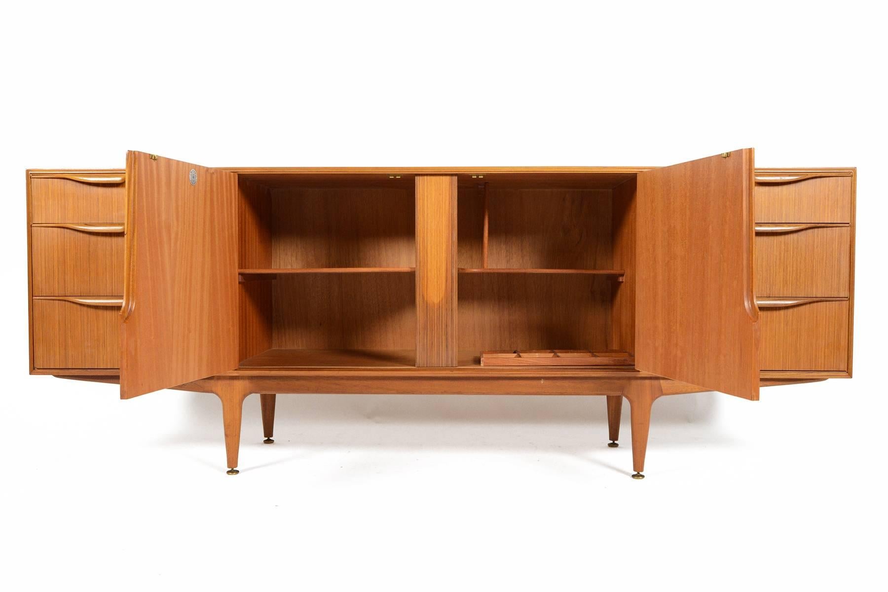 This large, low line teak credenza was designed and manufactured by A.H. McIntosh in the 1960s. Featuring carved teak drawer pulls and a sculptural teak base, this magnificent piece will look amazing in any modern home. Right interior even offers