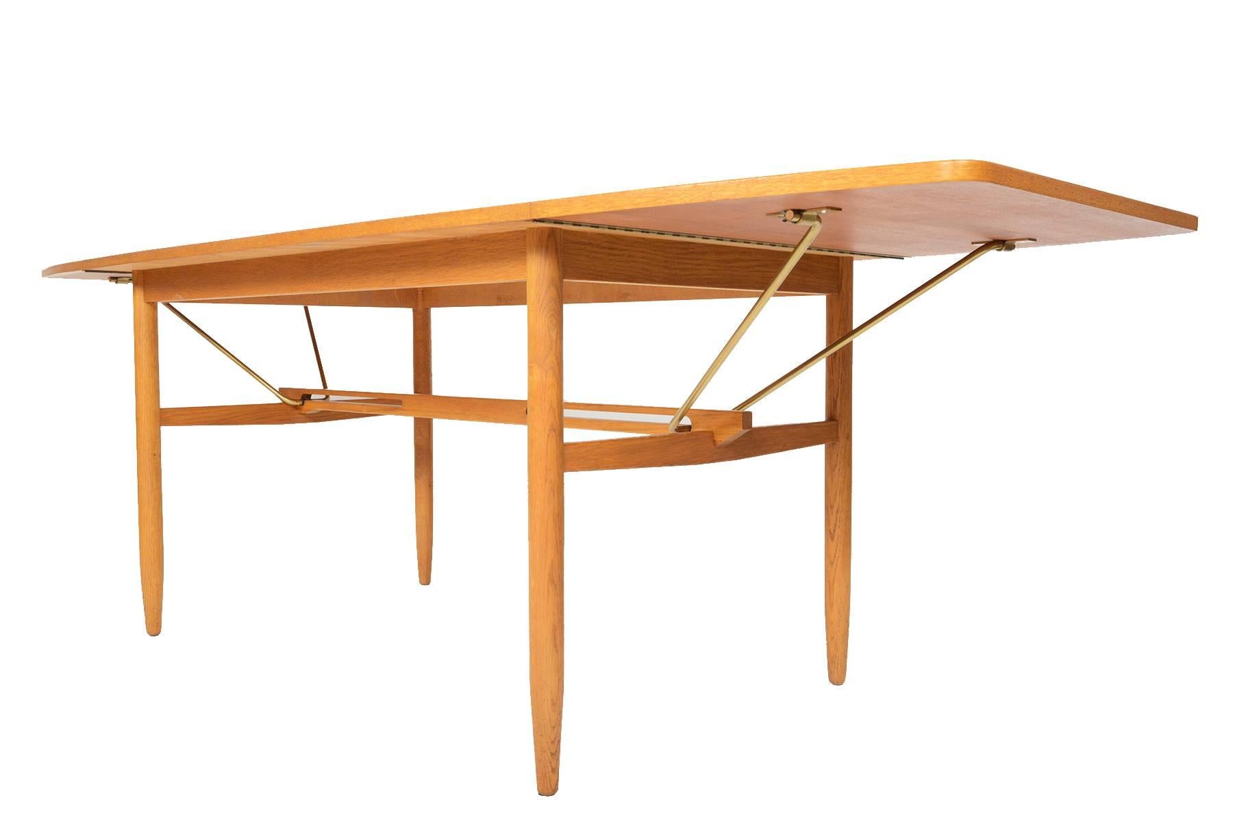 This gorgeous Scandinavian Mid-Century Modern drop-leaf dining table is crafted in teak and oak and offers a fantastic extension element. The teak slab is banded in oak and offers a tapered shape once extended. The oak spindle legs are braced with