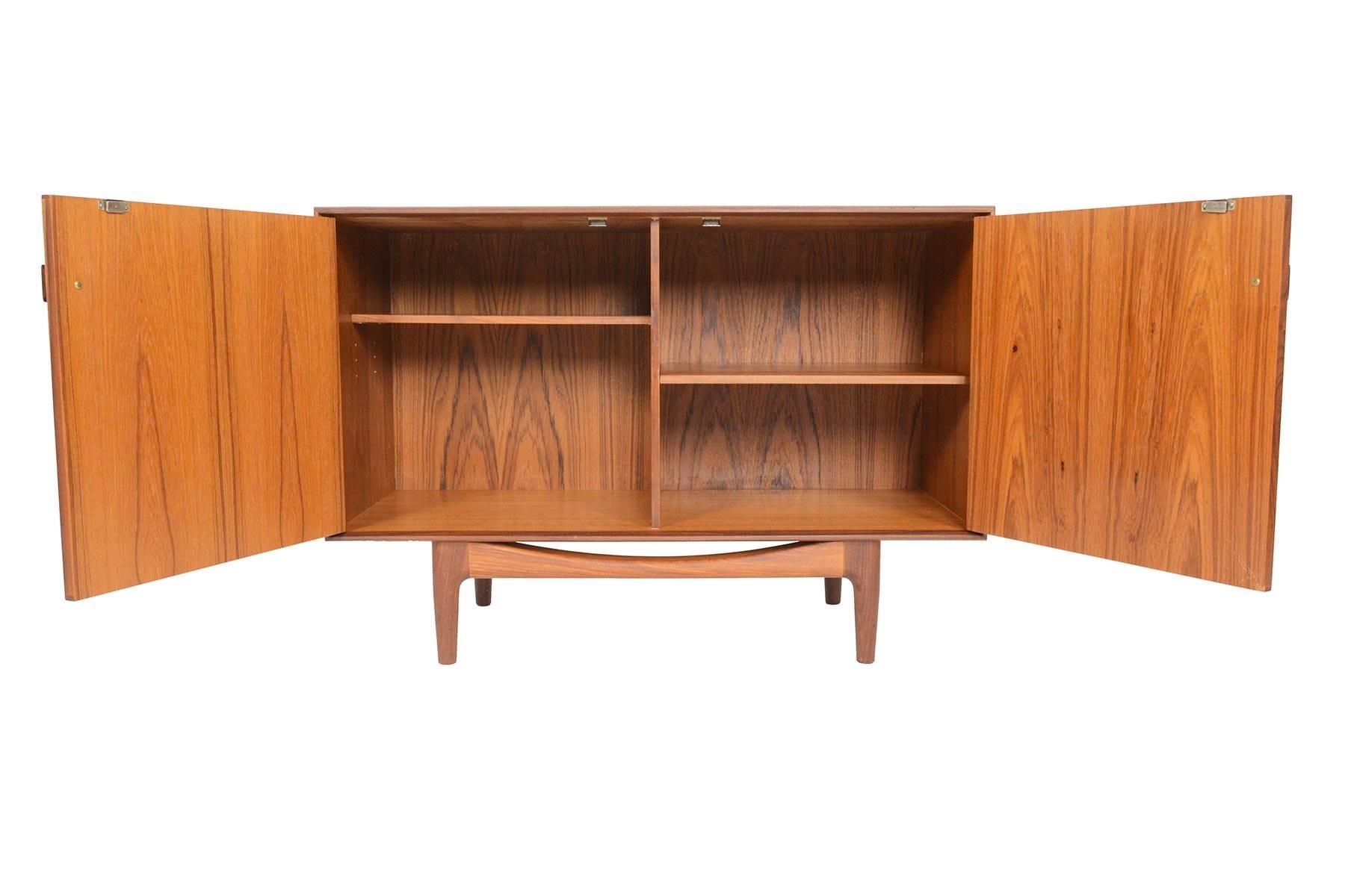 This small midcentury teak credenza was designed by Ib Kofod Larsen for G Plan in 1961 for the Danish range. Crafted in teak and afrormosia with handsomely refined lines, two wide doors open to reveal two bays with adjustable shelving. Finished on
