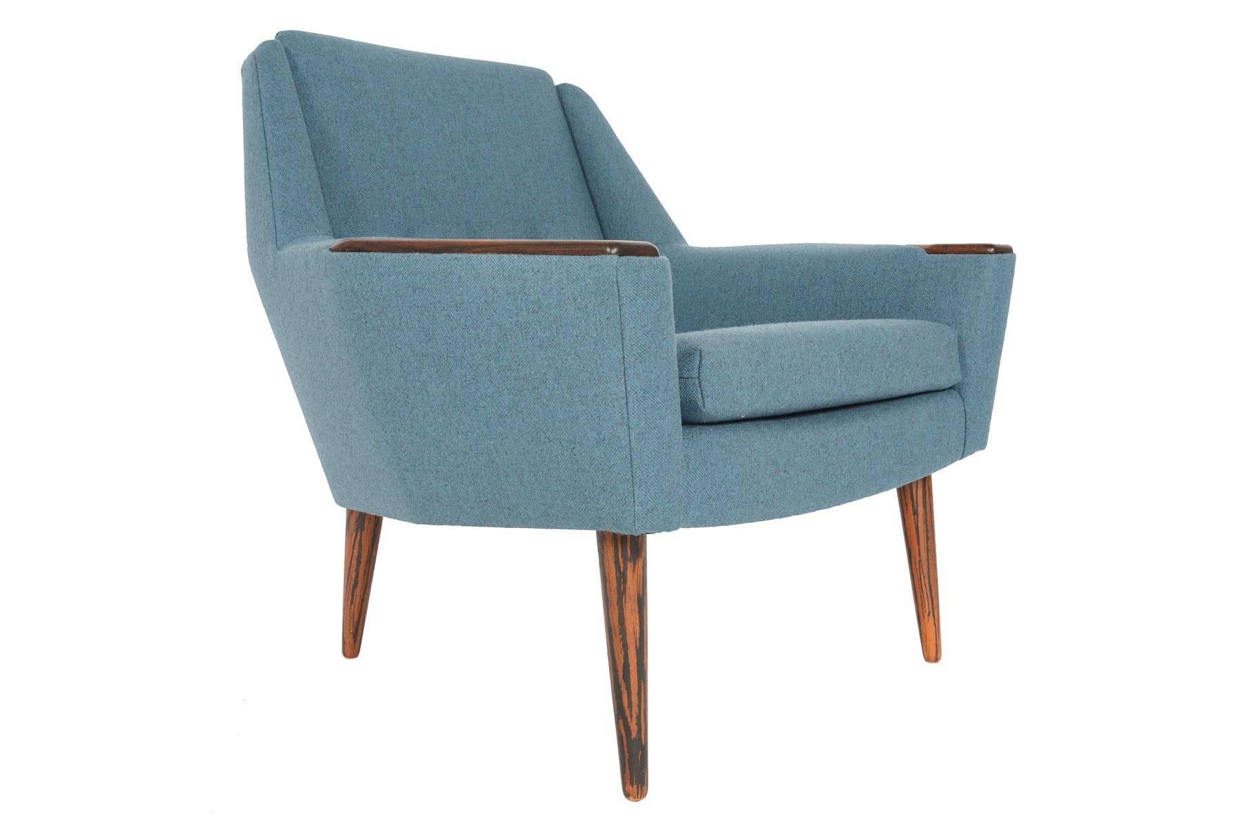 This Space Age Danish modern lounge chair features stunning angular lines of the early 1960s. Solid rosewood armrests add richness and character to this wonderful piece. Newly upholstered in cerulean Danish wool, this modern lounge will add plenty