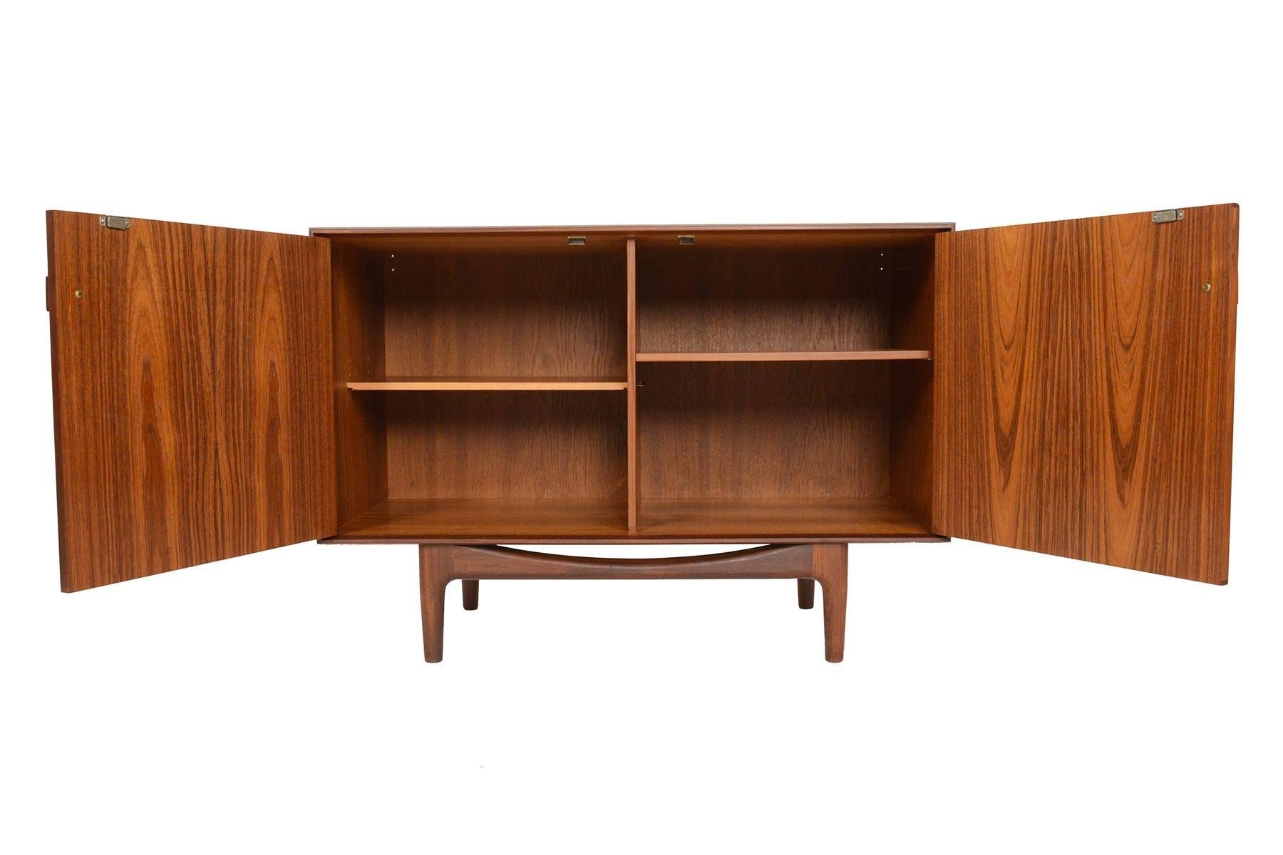This small midcentury teak credenza was designed by Ib Kofod-Larsen for G-Plan in 1961 for the Danish range. Crafted in teak and afrormosia with handsomely refined lines, two wide doors open to reveal two bays with adjustable shelving. Finished on