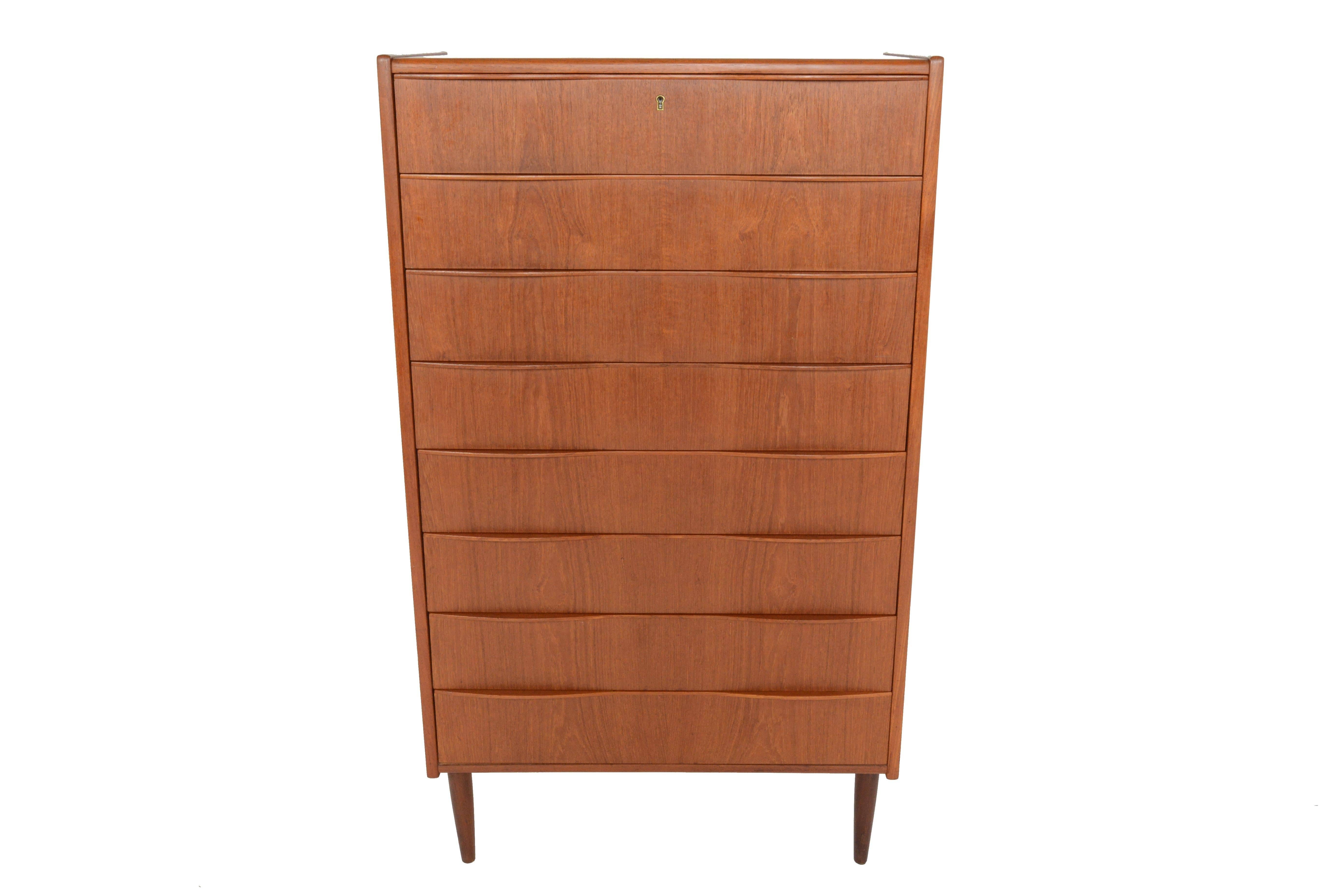 This gorgeous Danish modern midcentury teak highboy dresser is a fantastic storage solution for any modern home.  Eight large drawers accented by sculptural teak wave pulls provide ample storage space.  In excellent original condition.
 