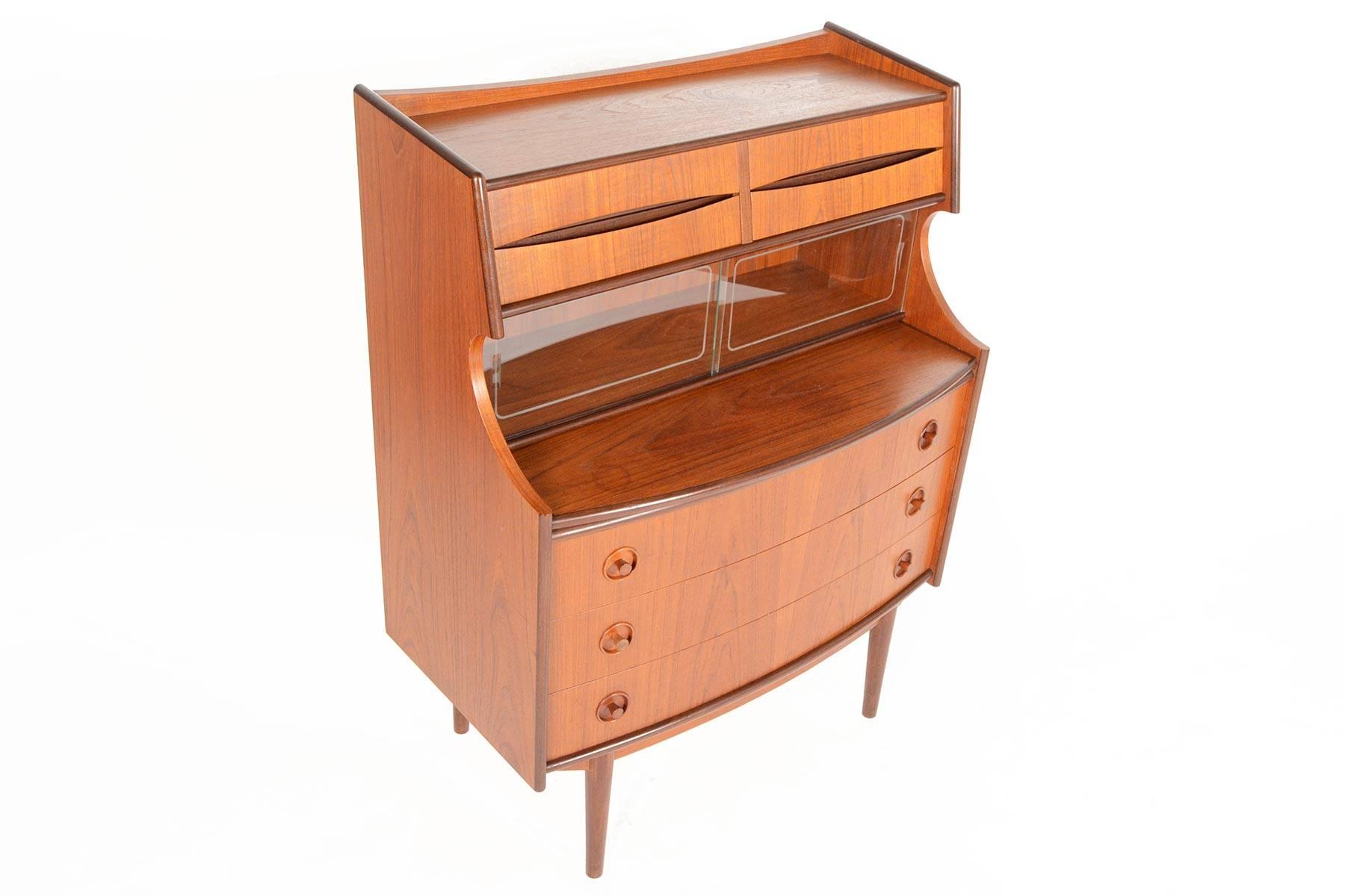 This incredible Danish modern secretary desk in teak hails straight from the 1960s! The center of this piece features a pullout desk and provides a spacious work surface. Two etched glass doors sit above. Four small upper drawers and three large,