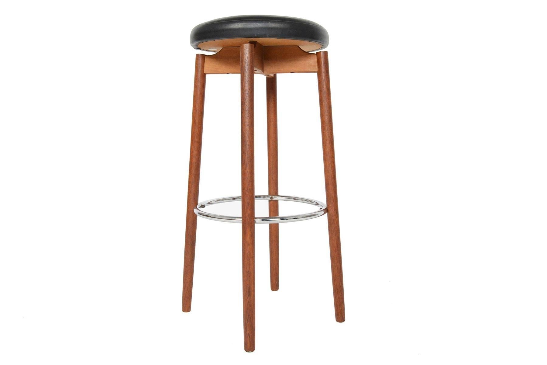This phenomenal pair of hard to find barstools was manufactured by Hugo Frandsen in Spottrup, Denmark in the 1960s.  Long, elegant teak legs are accented by a floating seat covered in original vinyl.  Round chrome footrests add style and