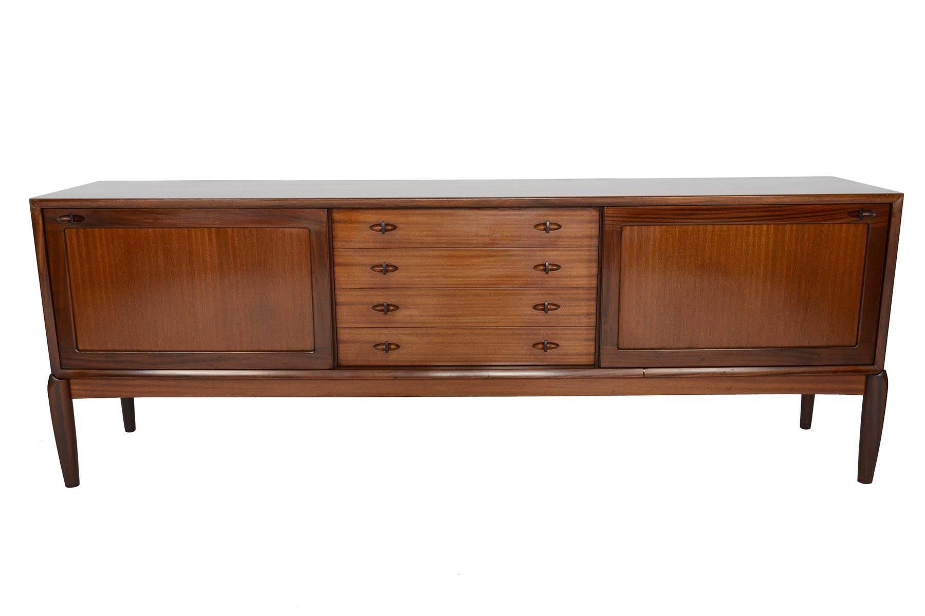 This classic Danish modern midcentury credenza was designed by H.W. Klein and manufactured by Bramin in the 1960s. Crafted in mahogany, this stately piece features two large doors which slide open to adjustable interior shelving. Four centre drawers