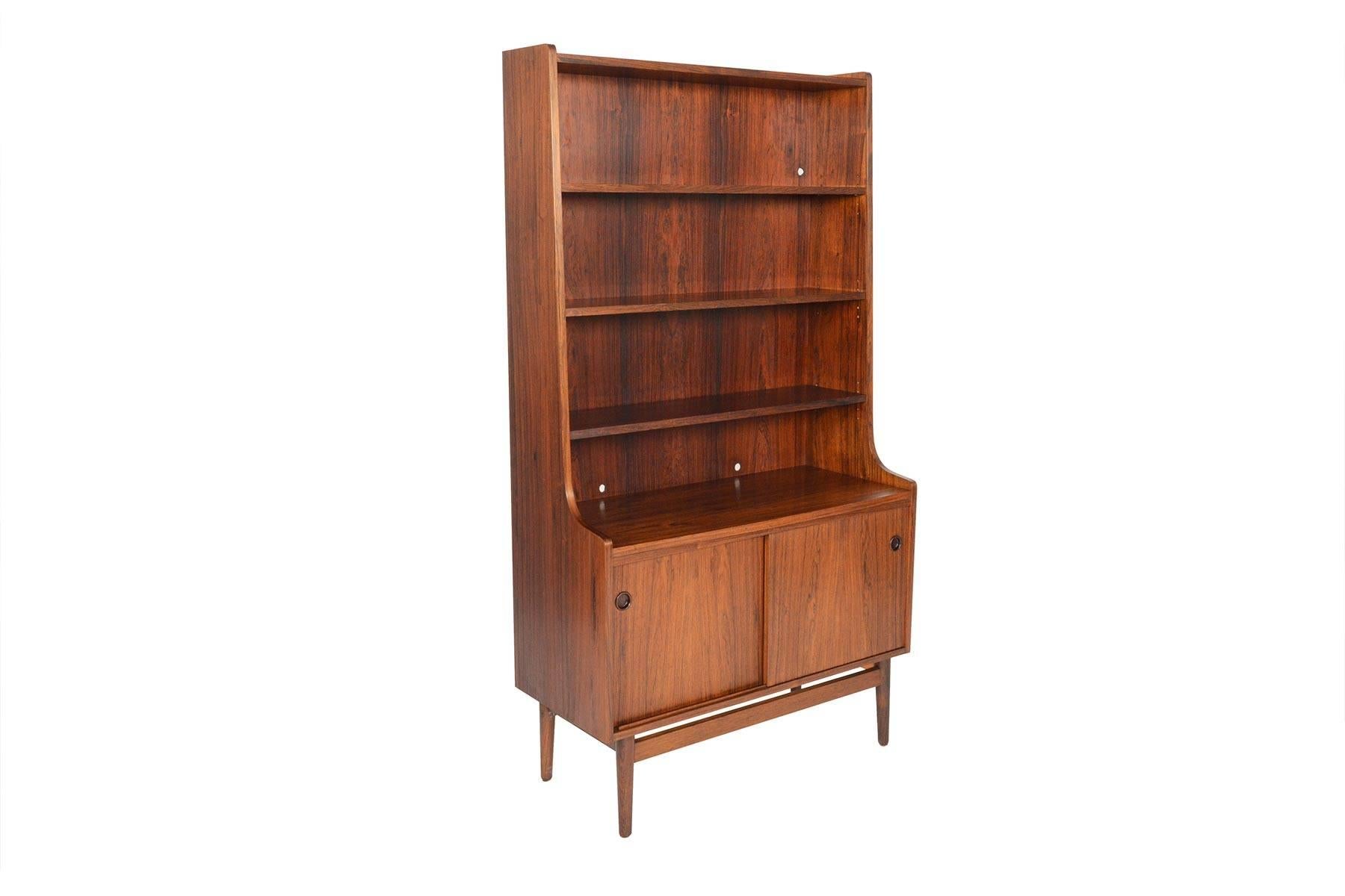 This beautiful Danish modern midcentury bookcase in Brazilian rosewood was designed by Johannes Sorth for Bornholm Møbelfabrik, Nexo in the 1960s. The tall, upper hutch features three adjustable shelves. The lower cabinet showcases two sliding doors