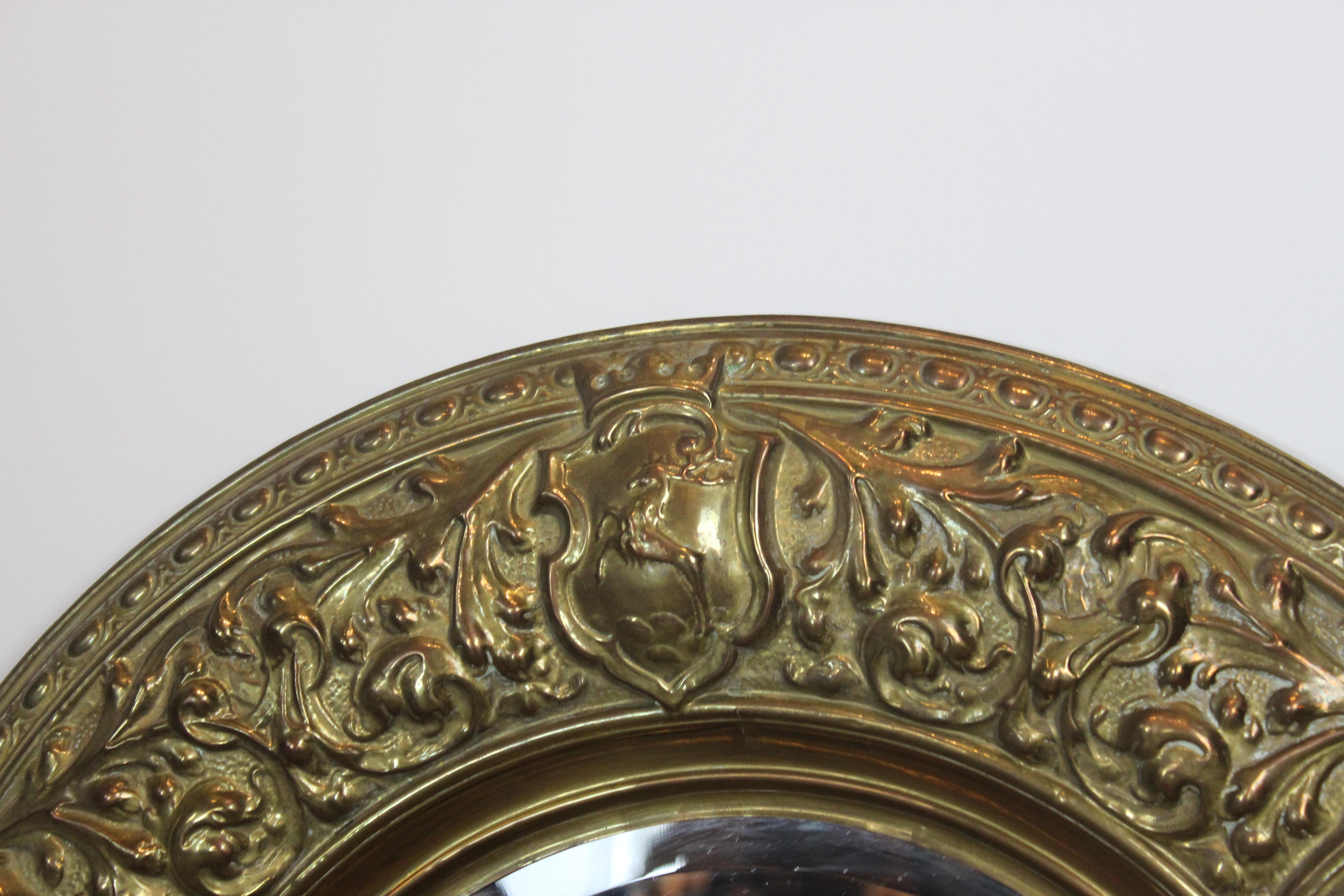 Pair of embossed brass round shape medieval theme mirror. The mirrors are beveled edge.