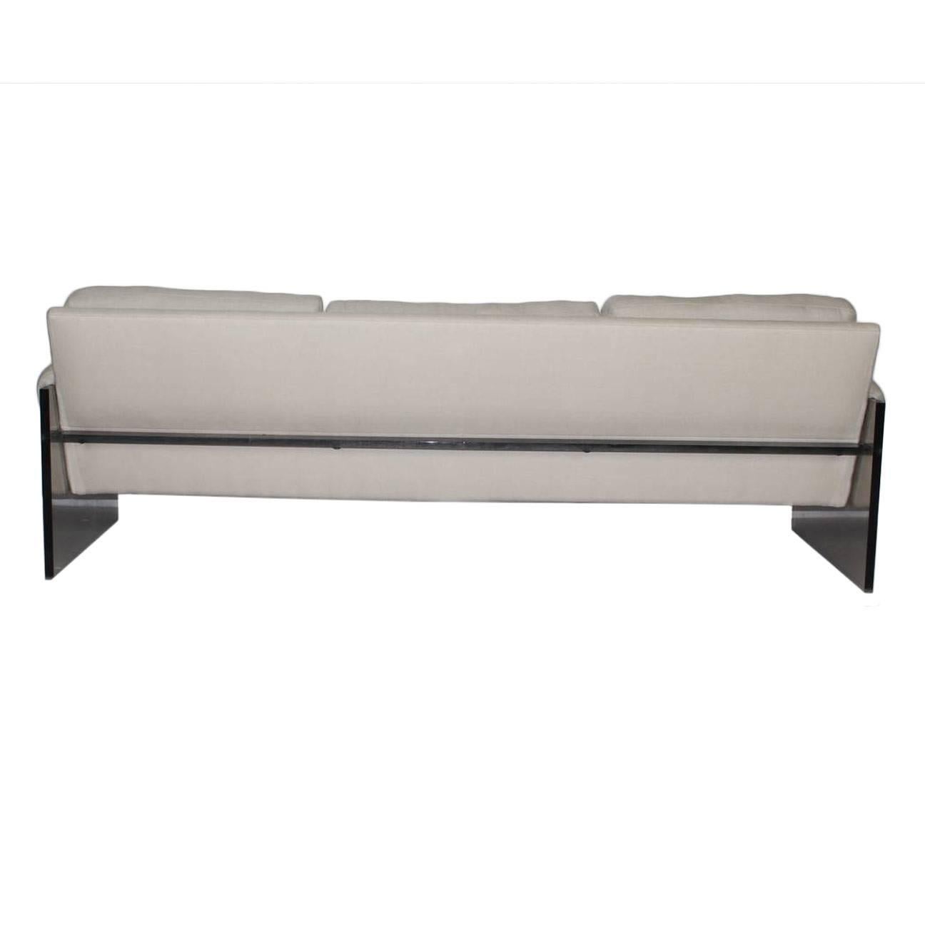 Milo Baughman Lucite three-seat sofa. The cushions and the arms are upholstered in cotton light gray. The cushions are foam.