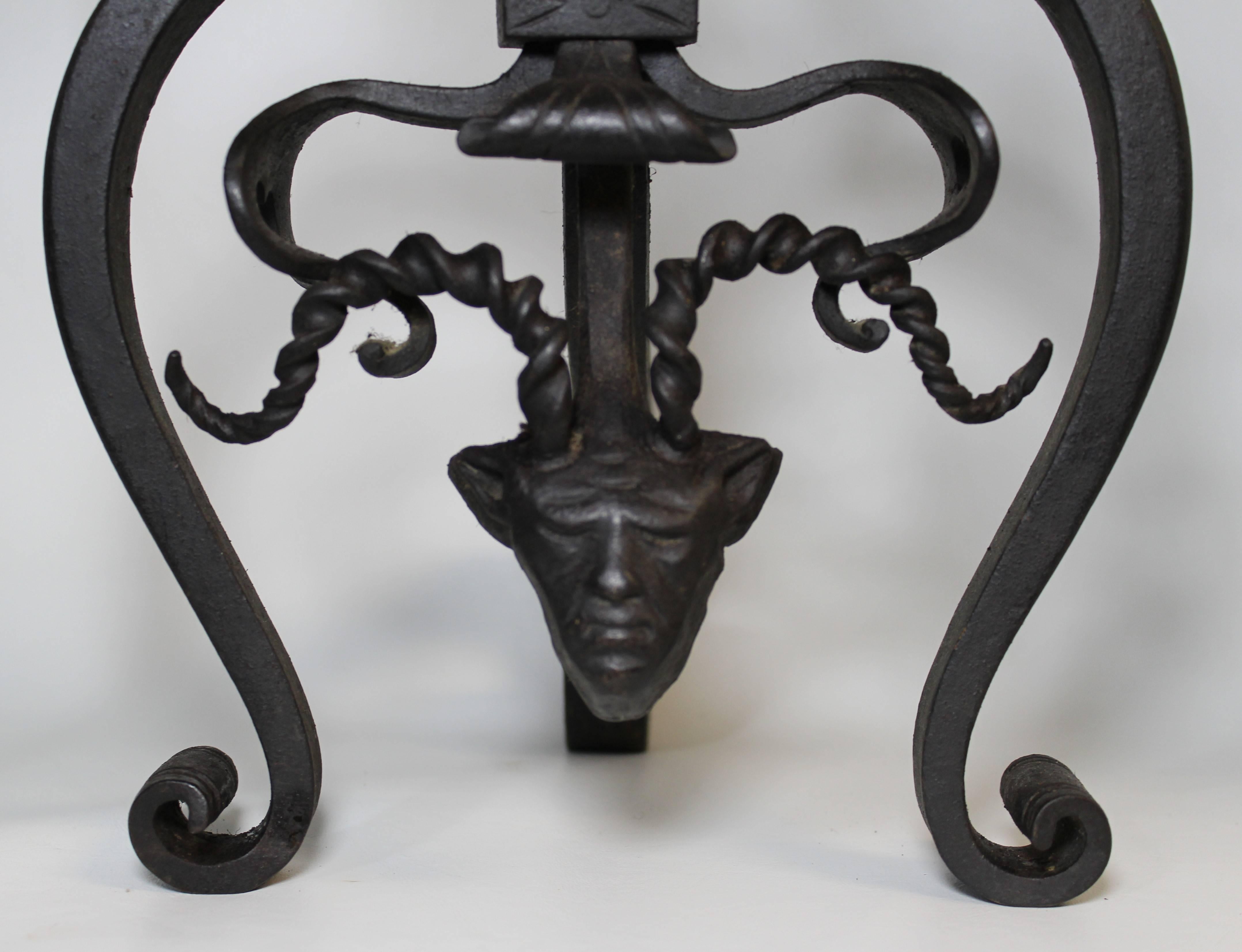 Pair of Gothic Revival wrought iron andirons with figural horned devils and fireplace tools.