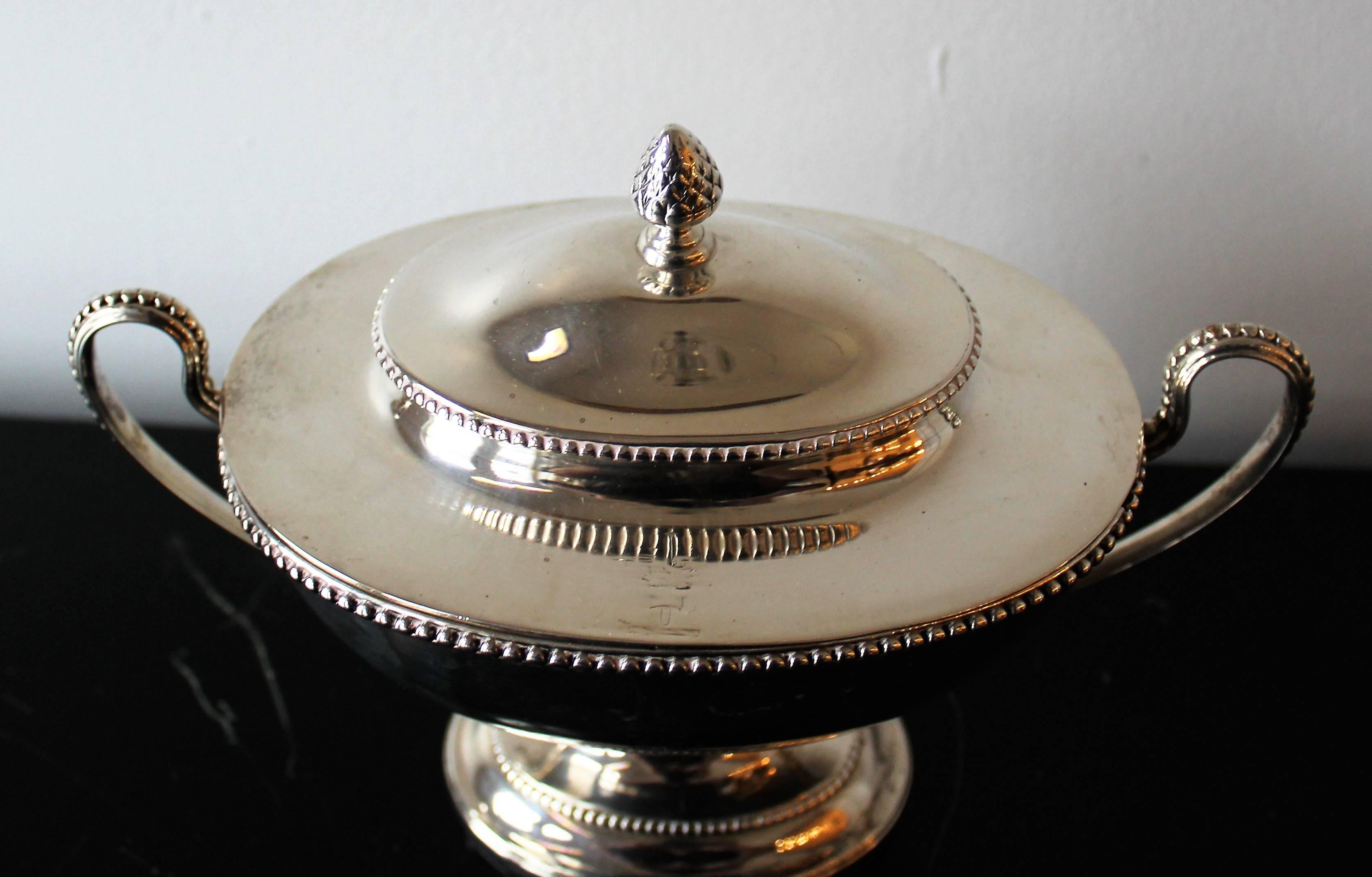 A pair of English George III sterling silver sauce tureens by 18th Century London silversmith Augustin Le Sage. The tureens have single scroll handles and raised pedestal beaded feet.  The covers are detachable and also feature beading while the